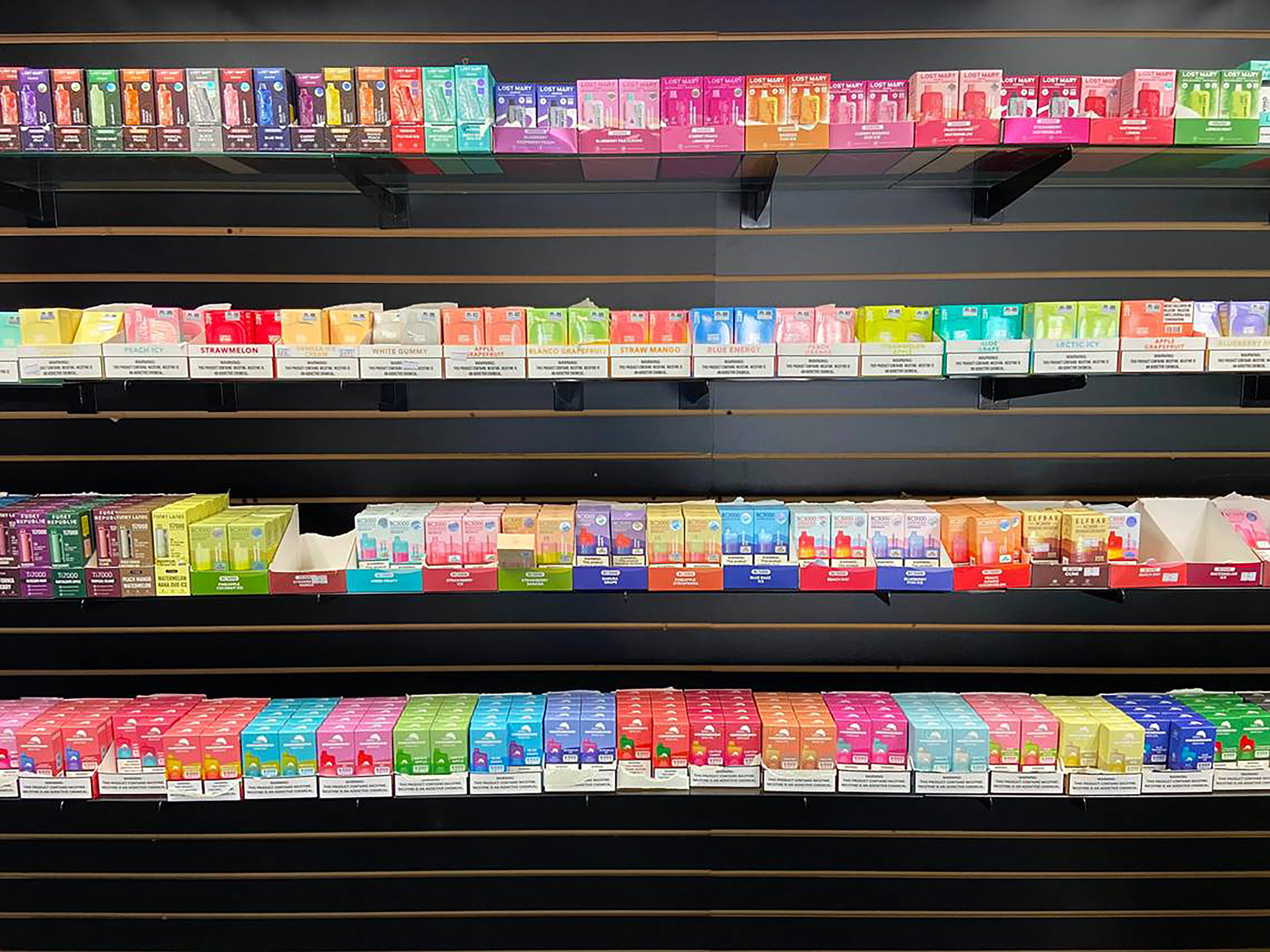A photo of colorful vape juice products lined up on shelves in a store.