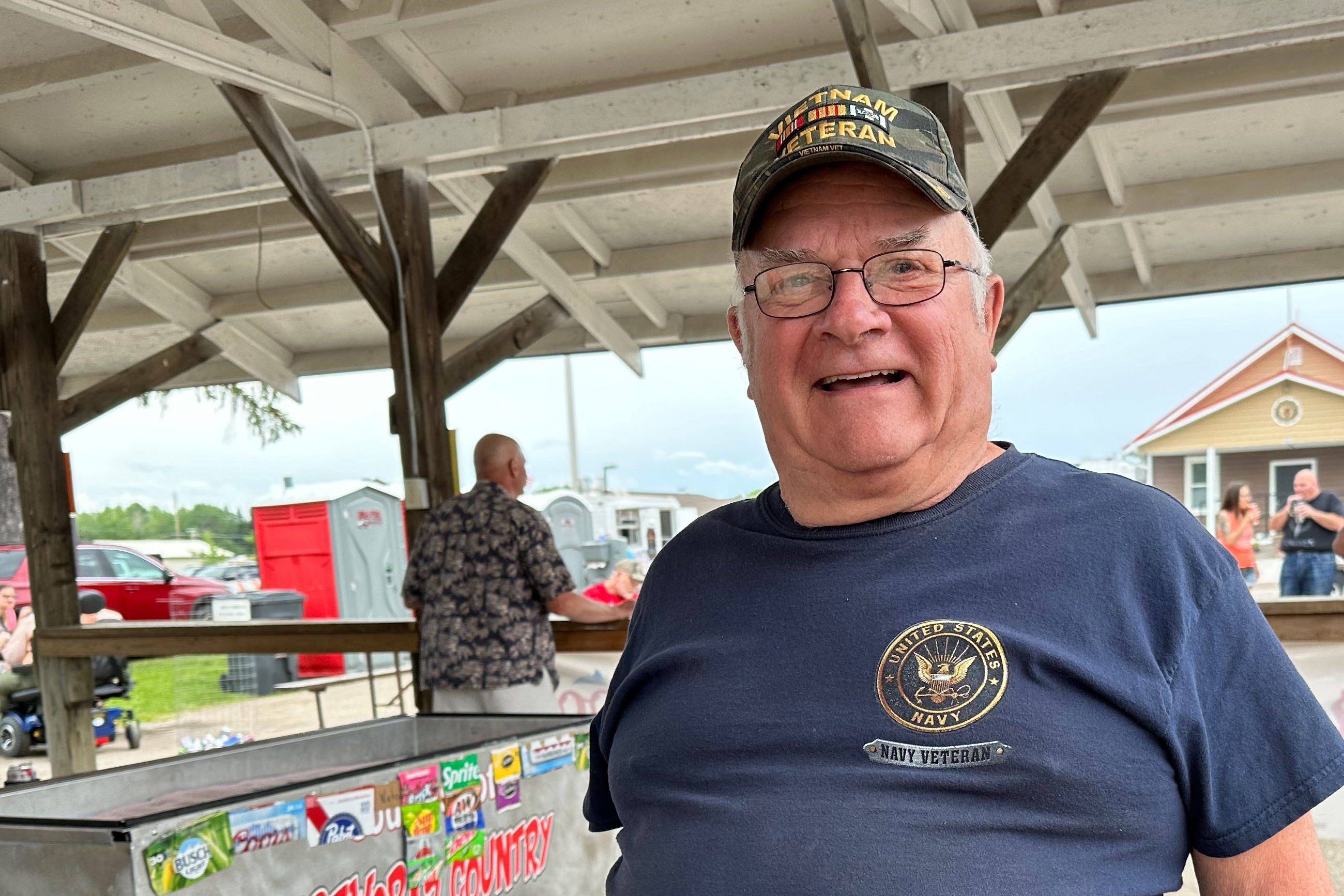 Bob Prelipp, an older man, looks twards the camera as he talks. he wears a veteran's hat and a T-shirt that says, "United States Navy."