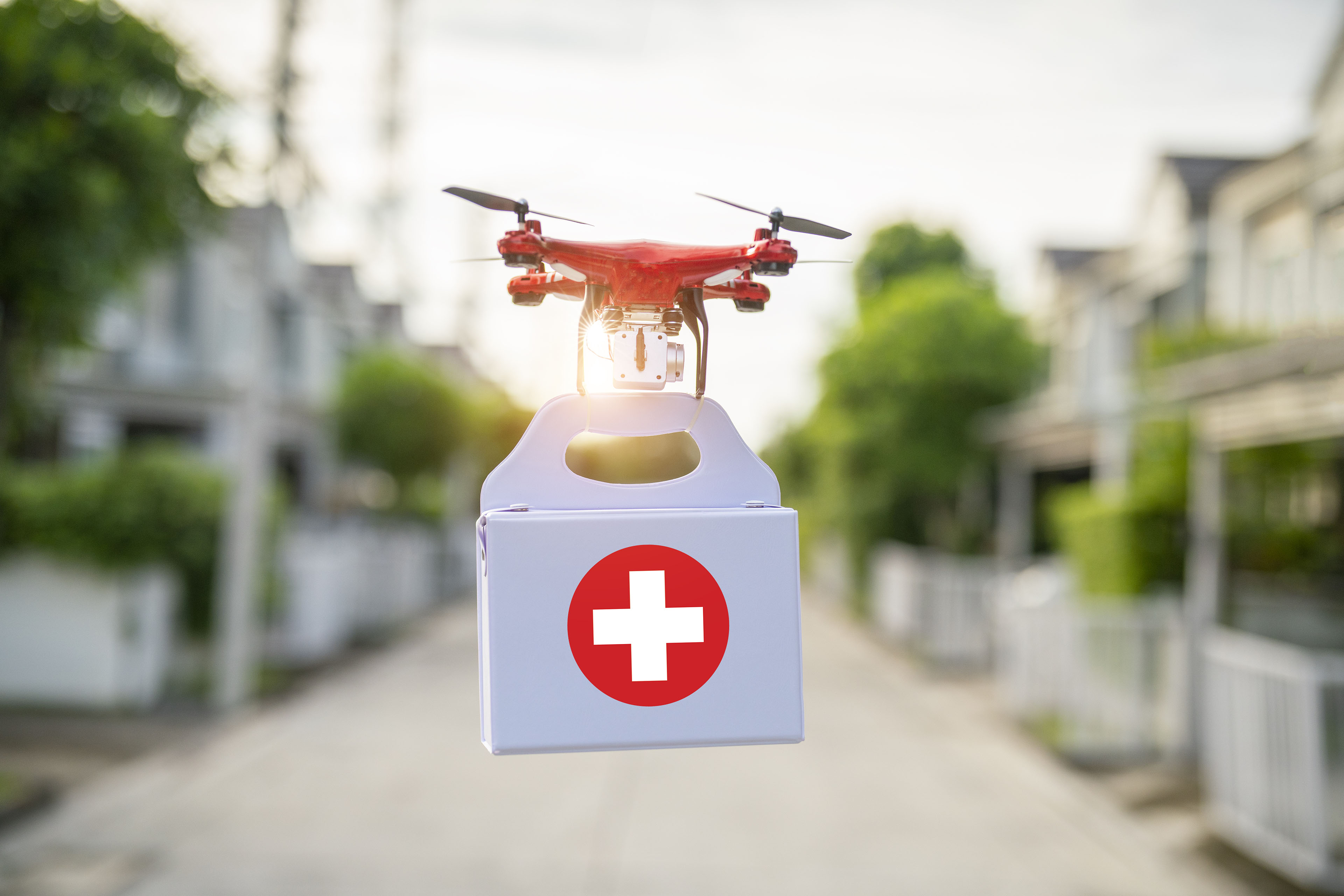 A photo illustration of a drone carrying a emergency medical kit.