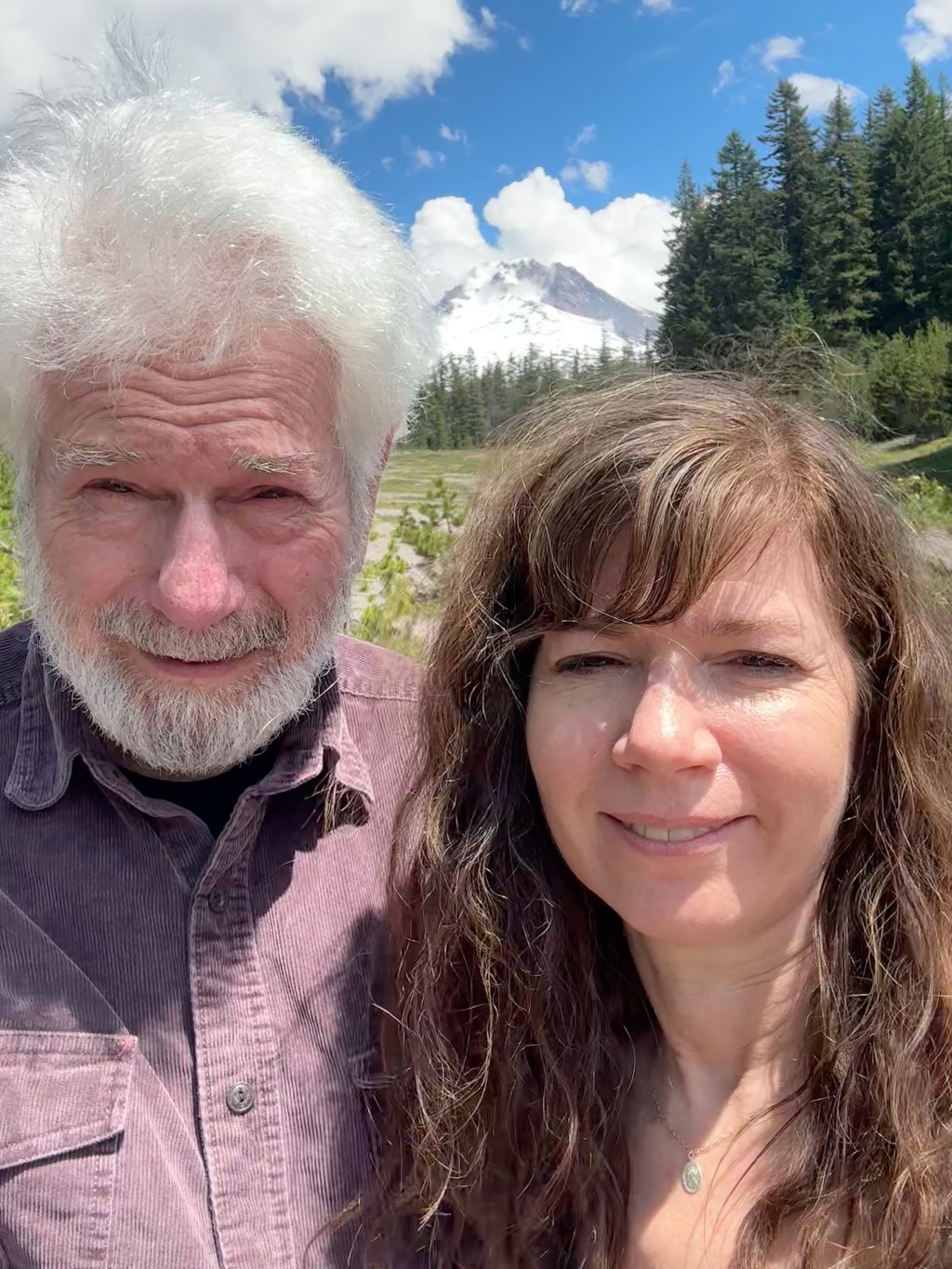 A man with white hair and a beard stands next to a brown-haired woman