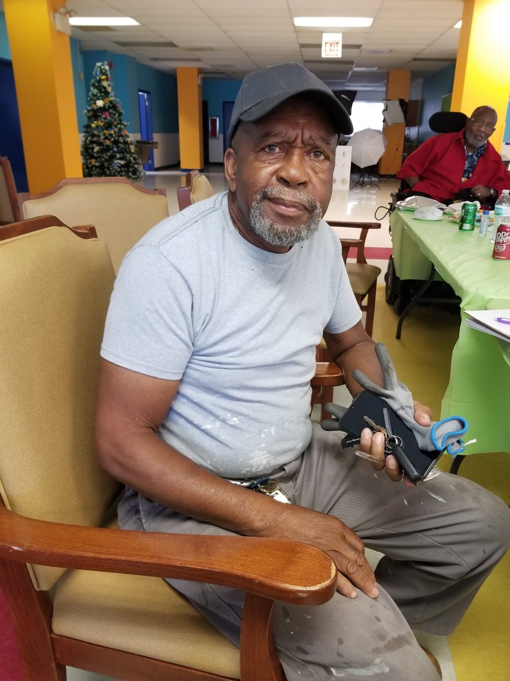 A man in a cap and tshirt is seated on a chair