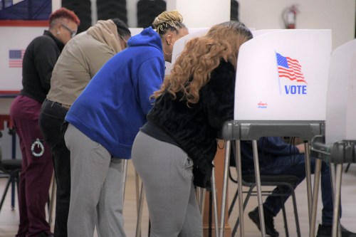 A photo of women voters behind privacy screens filling out ballots.