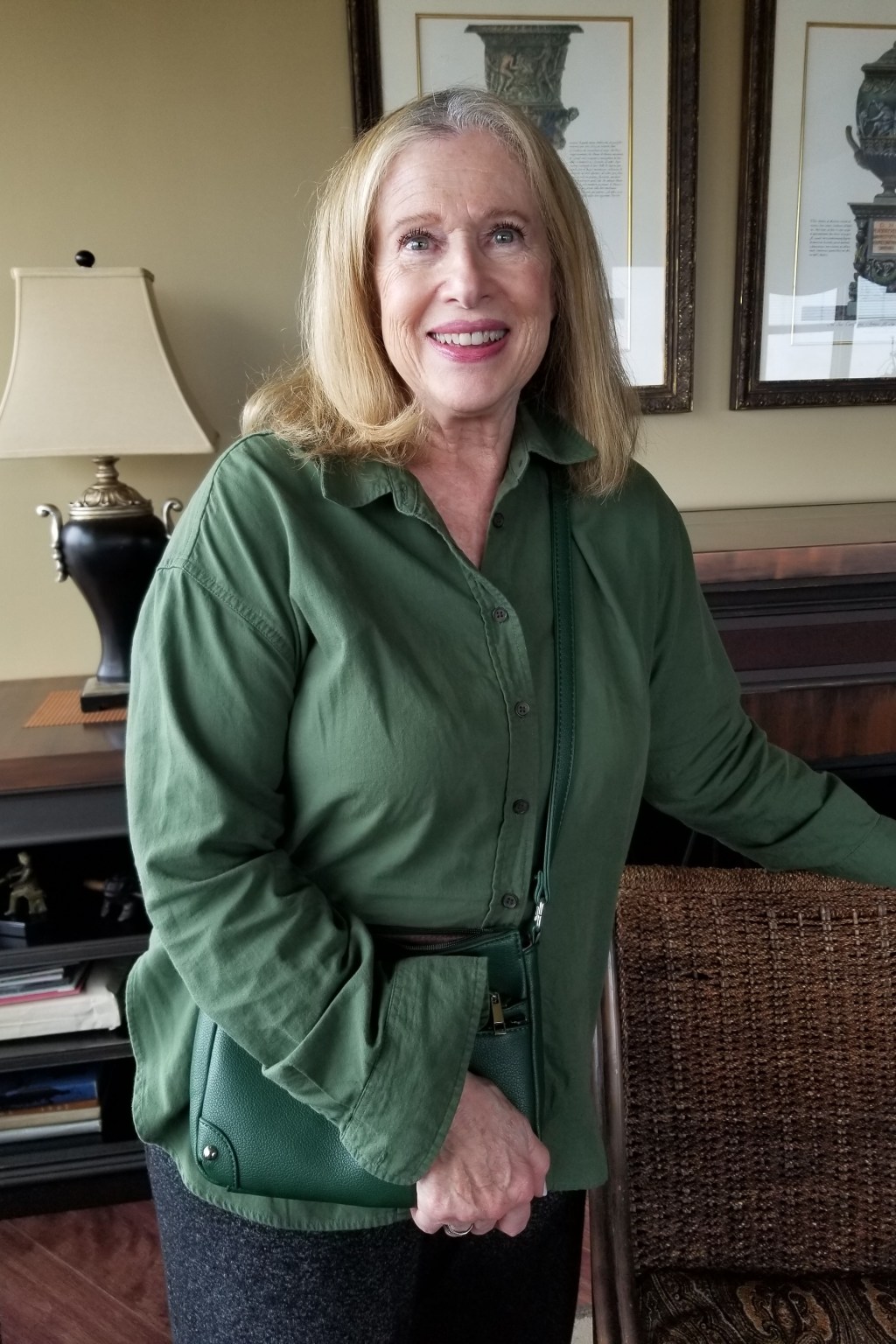 Jobie Stern, a senior woman with blonde hair, stands in a room and wears a green jacket.