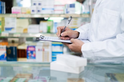 A photo of a pharmacist writing notes on a clipboard.
