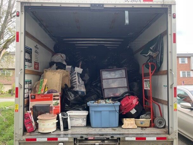 A photo of a box truck's cargo area filled with trash bags, boxes, and other items.