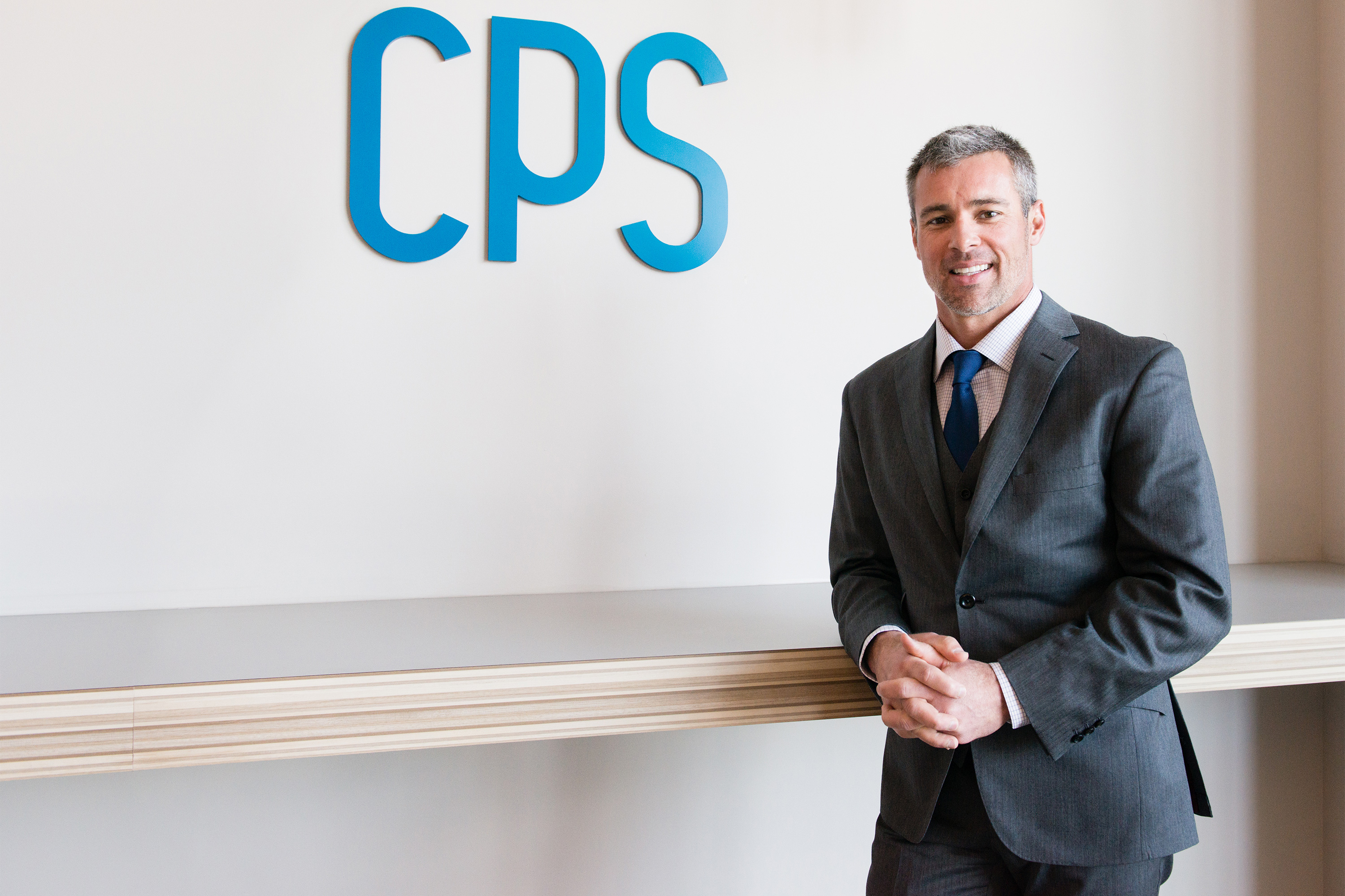 A photo of John Estin Davis posing in front of a wall with the Comprehensive Pain Specialists logo on it.