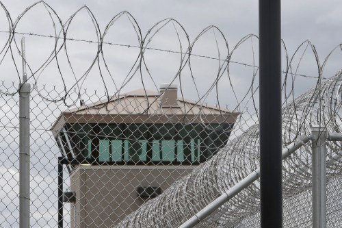 A photo of a barbed wire fence seen in front of a guard tower.
