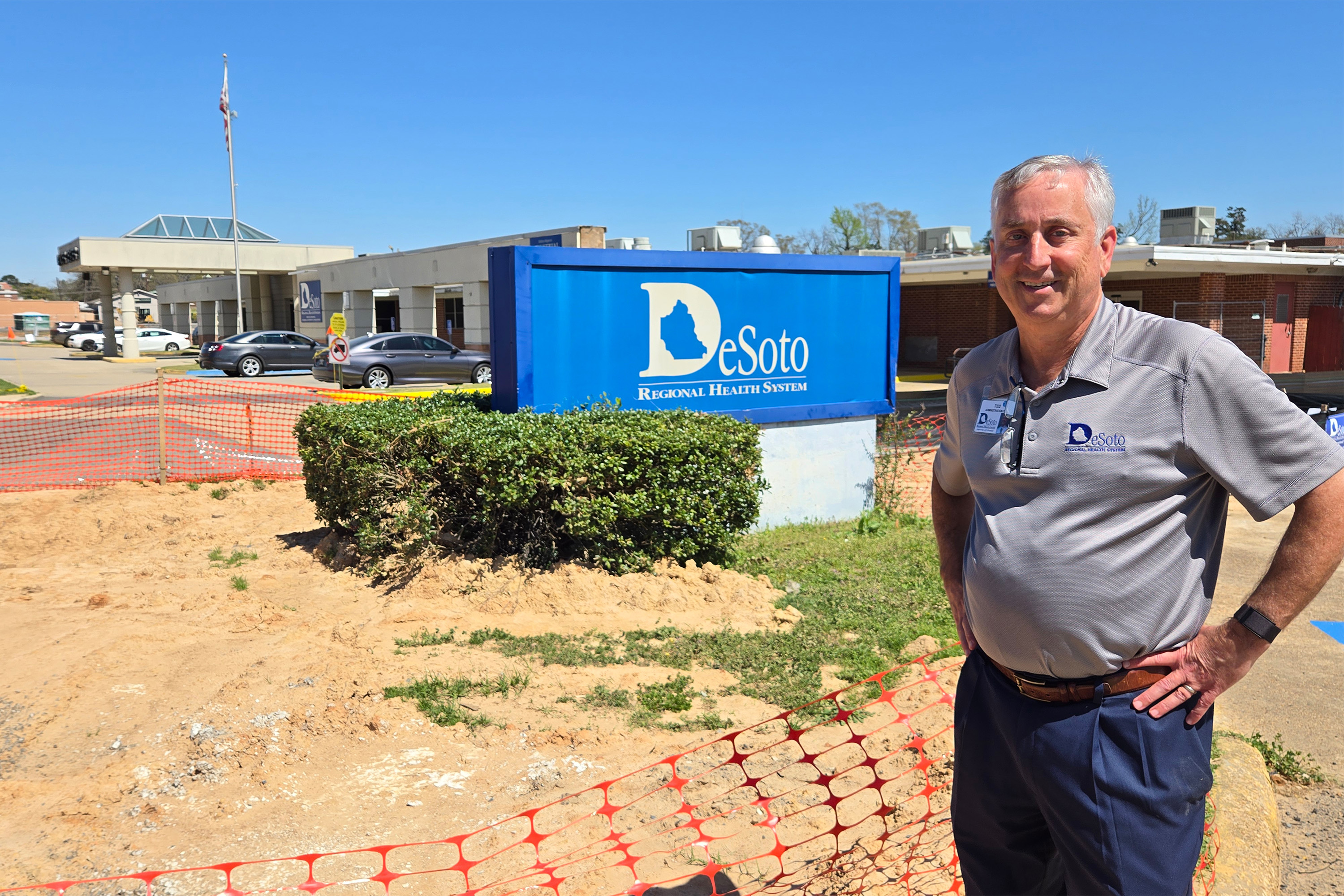 A photo of Todd Eppler posing by a sign for Desoto Regional Health System.