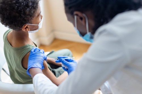 A young child receiving a vaccine from a female doctor