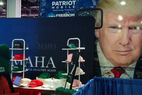 A photo of a merch counter with baseball caps and beanies in various colors bearing the "Make America Healthy Again" slogan.