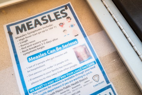 A photo of a flyer that reads, "Measles: Measles symptoms include high fever, cough, runny nose, red and watery eyes, rash breakout 3-5 days after symptoms begin. Measles can be serious. 1 out of 5 people who get measles will be hospitalized. One person can make 12 people sick. If someone in your family has measles, please try to stay away from other people."