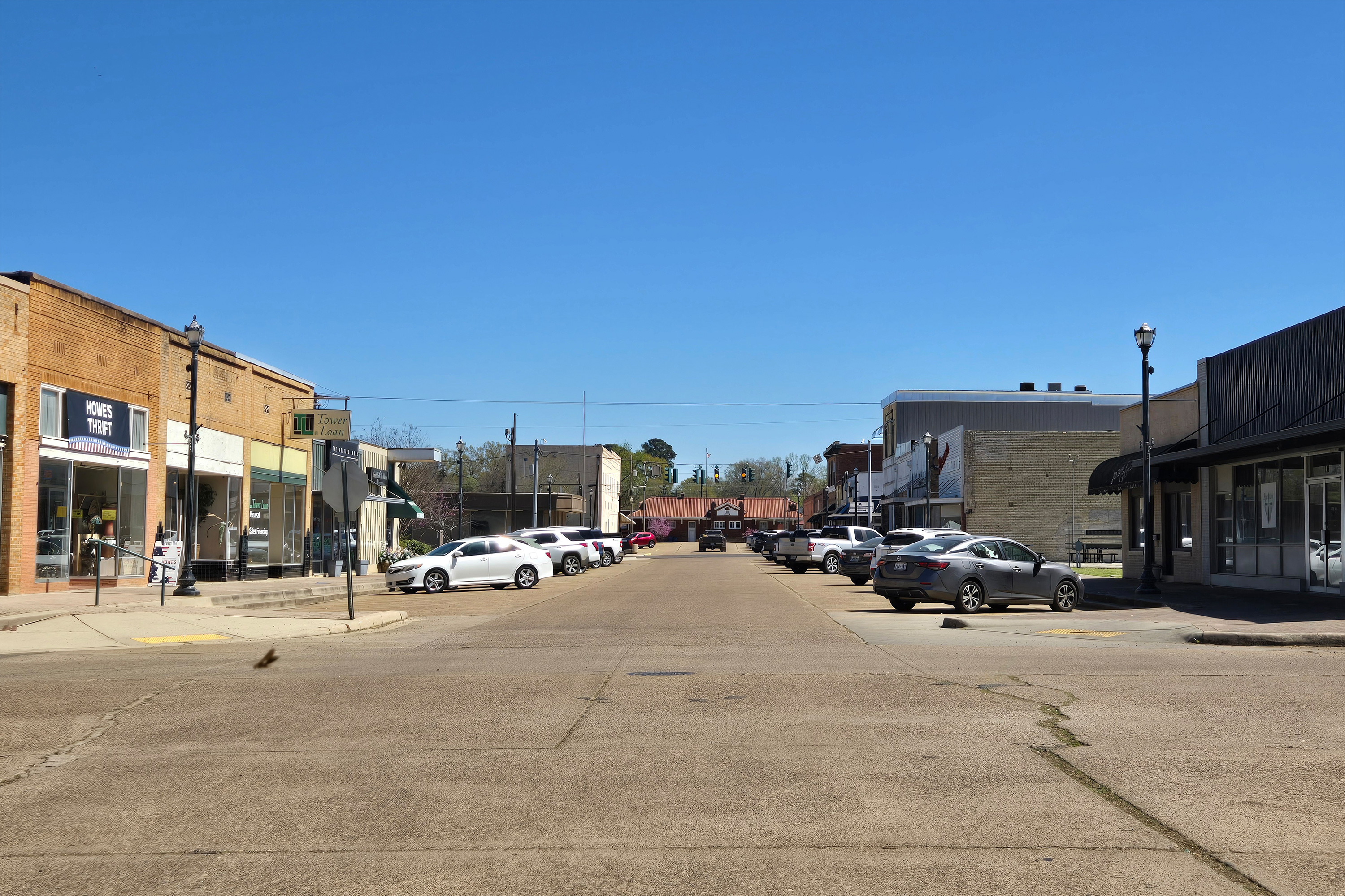 A photo of a street in Vivian, Louisiana. Cars are pulled into parking spots and small shops line the street.