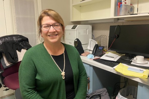 A photo of a woman sitting for a photo in an office.