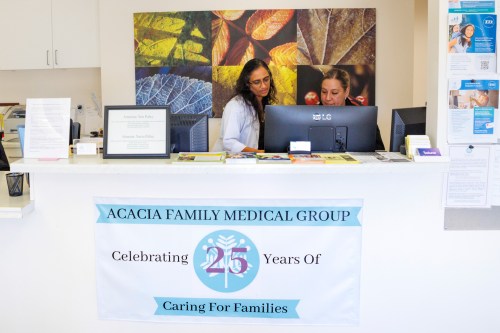 A photo of a doctor speaking to a colleague at the front desk of a doctor's office.