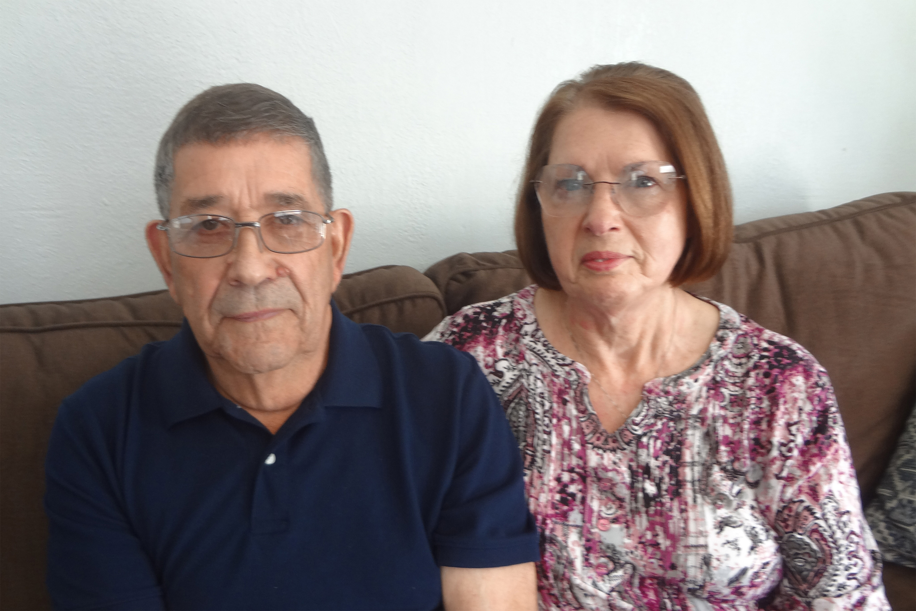 A photo of a man and woman sitting together on a sofa.