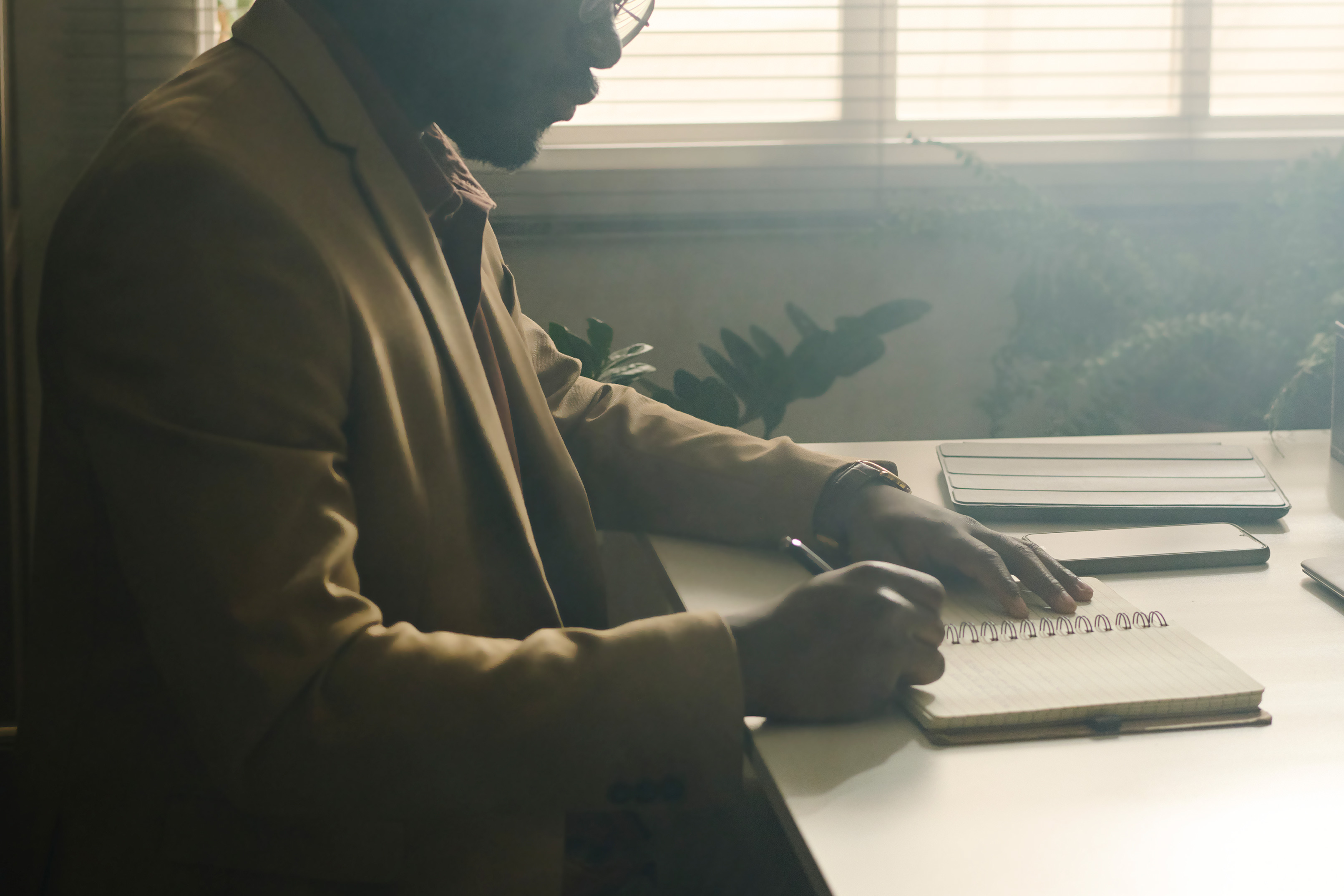A photo of a psychologist writing in a notebook in a dark office.