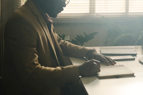 A photo of a psychologist writing in a notebook in a dark office.
