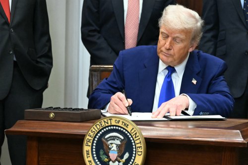 A photo of President Trump seated at a desk, signing an executive order.