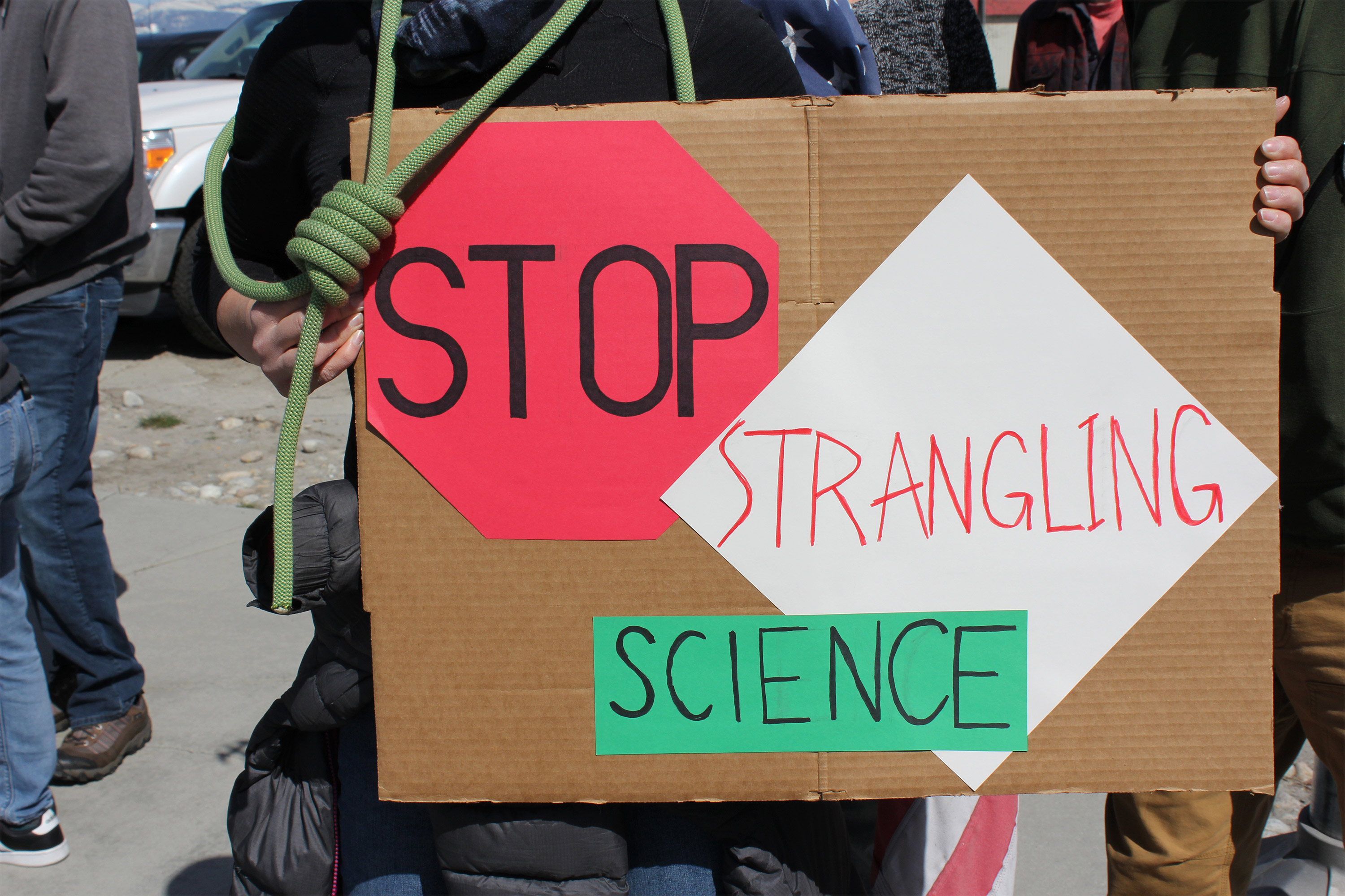A photo of a sign that reads, "Stop strangling science."