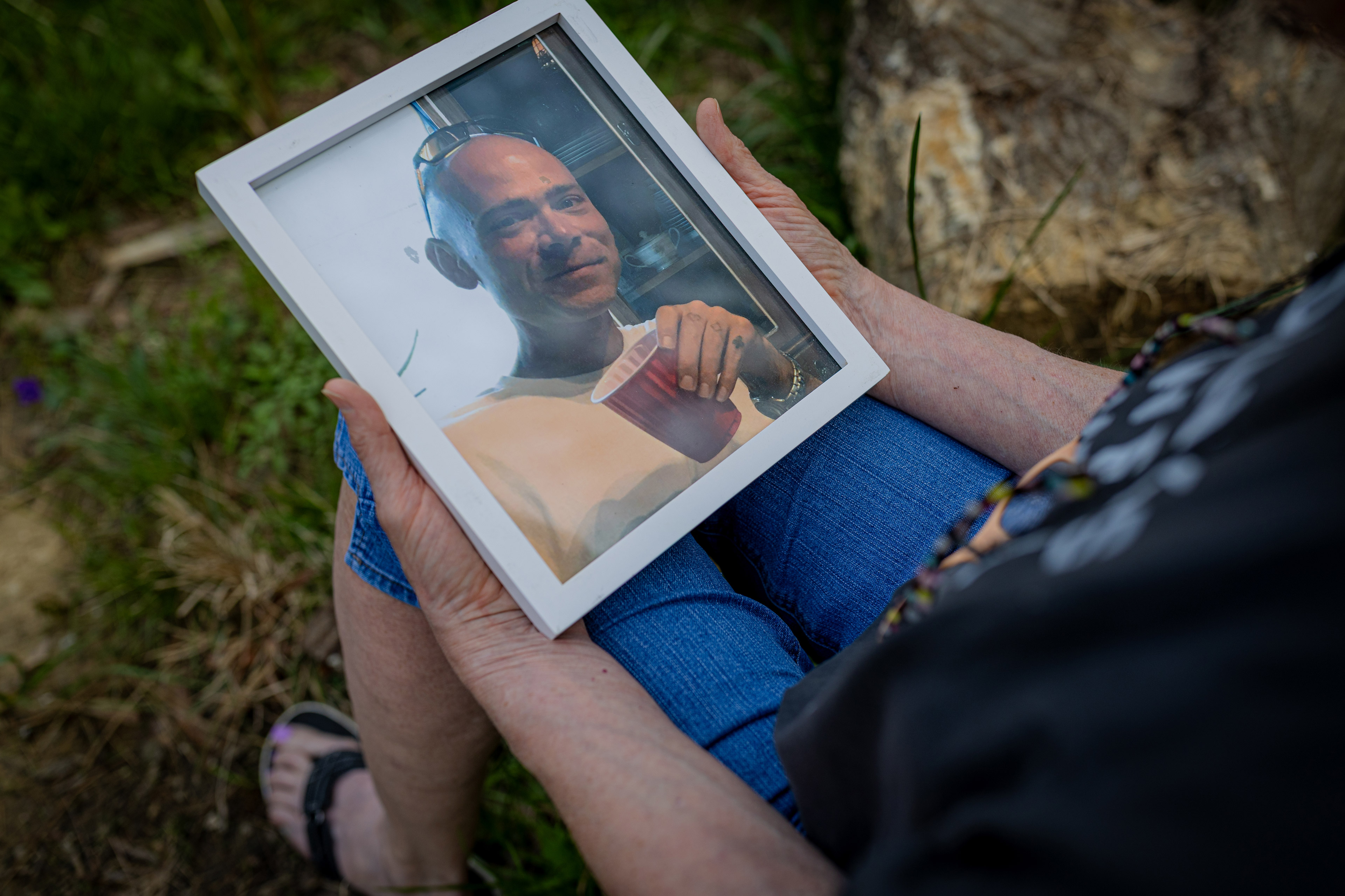 A photo of Pamela Moser holding a framed photo of her son, Brian Rigsby.