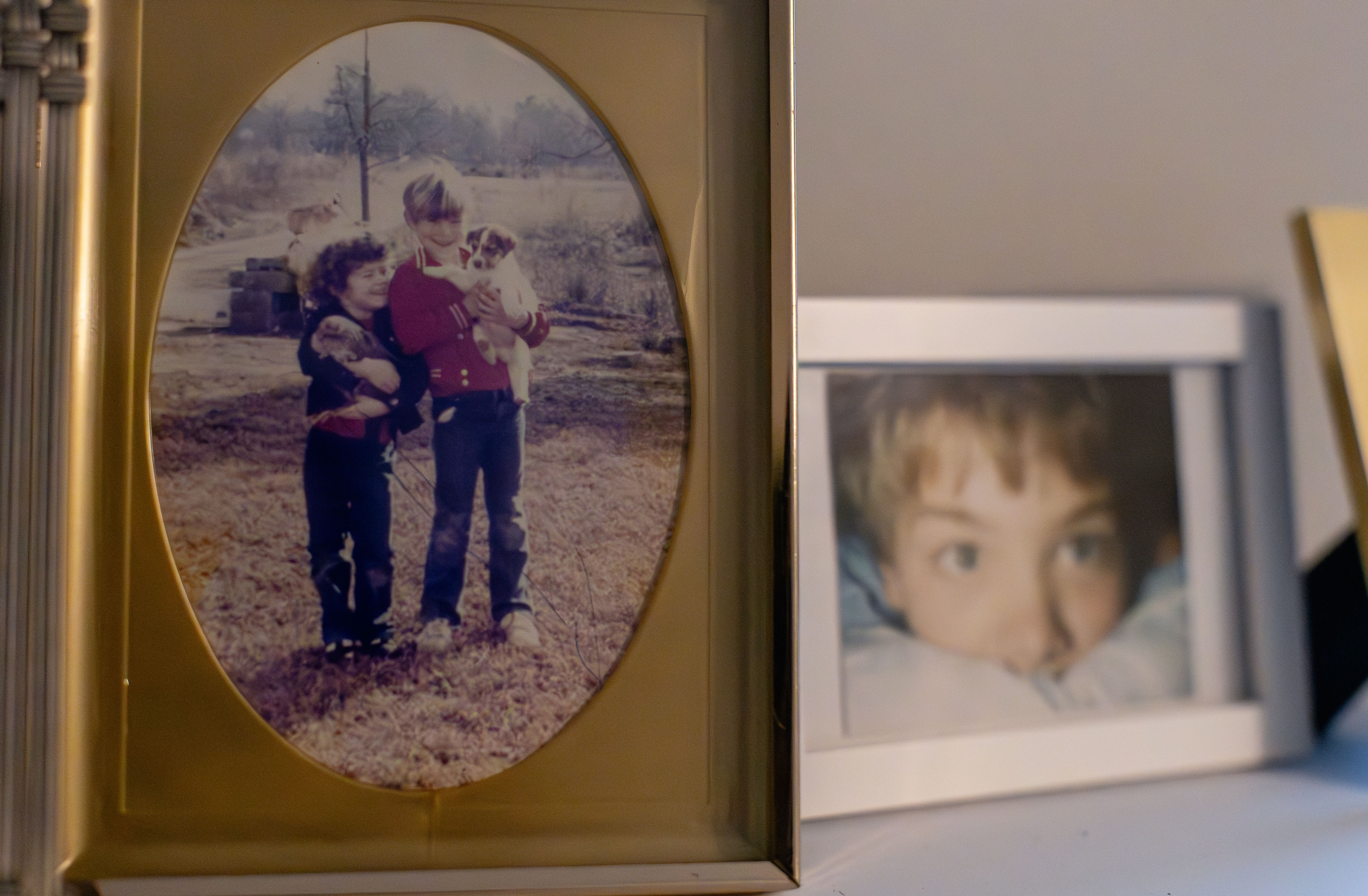 Old photos on a shelf show a young boy and a picture him with a young girl together.