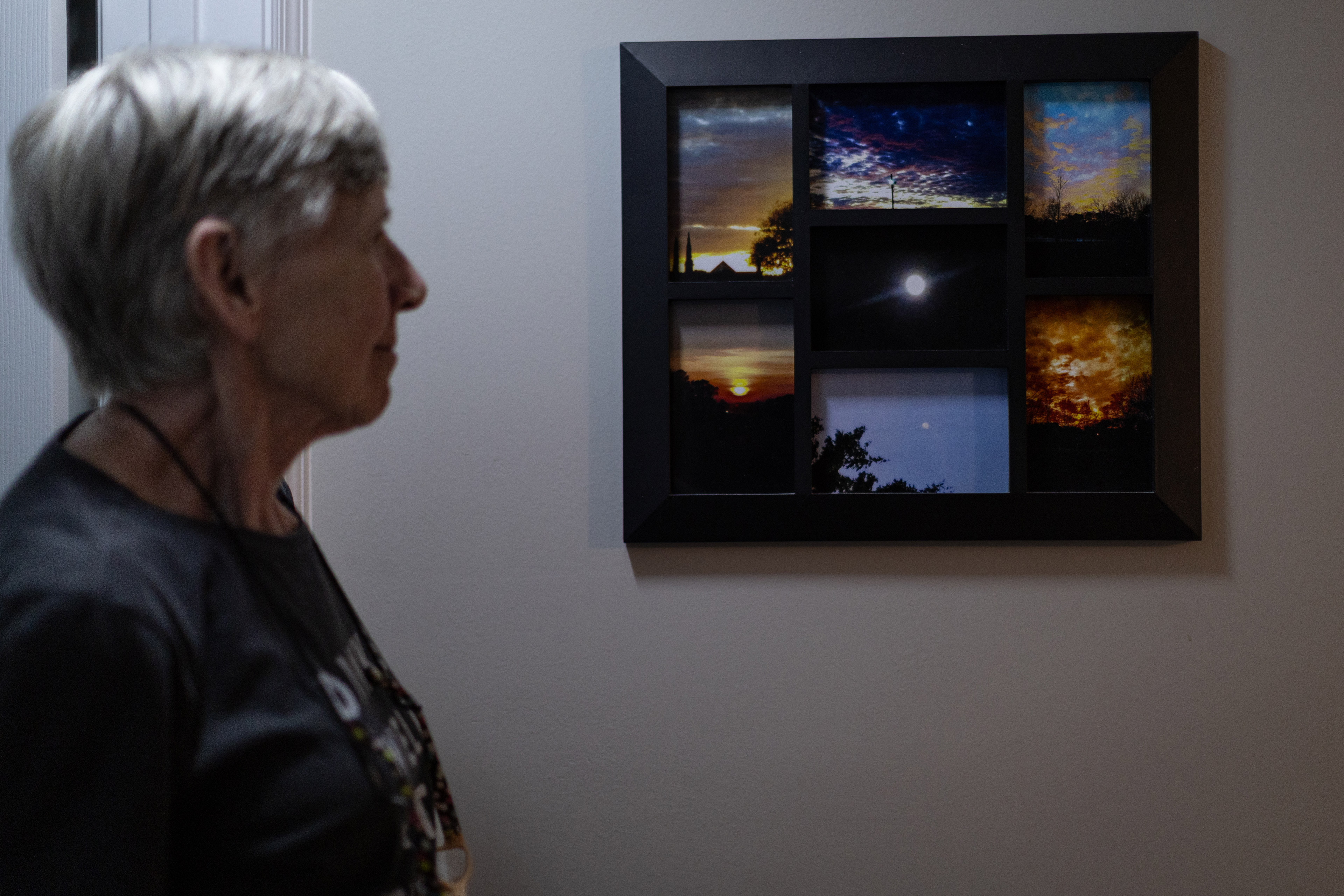 A photo of Pamela Moser standing by a collage frame with seven photos taken by her son of the sky.