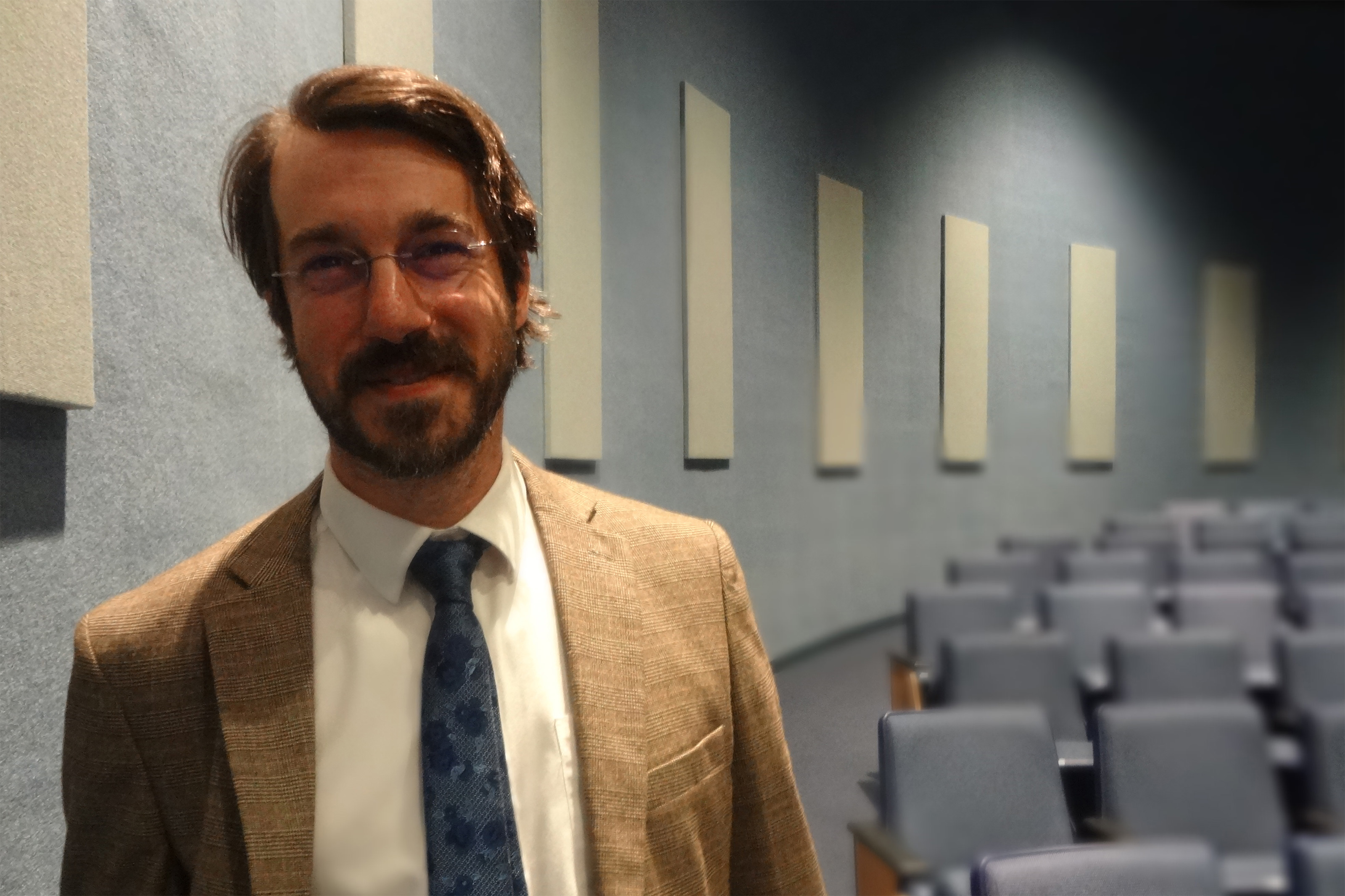 A photo of a lawyer standing for a photo in an auditorium.