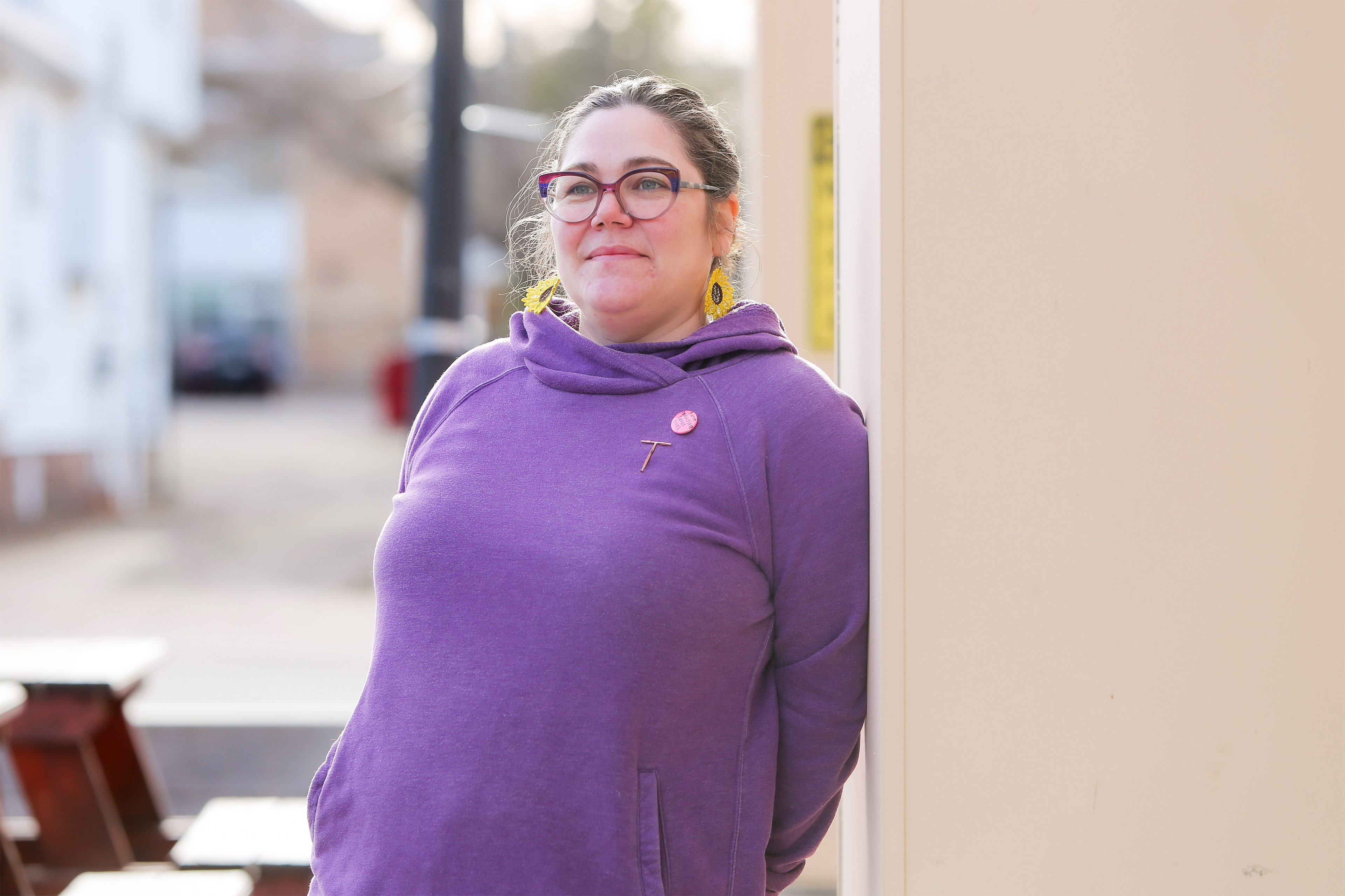 A photo of a woman posing for a portrait outdoors. She leans against a wall.