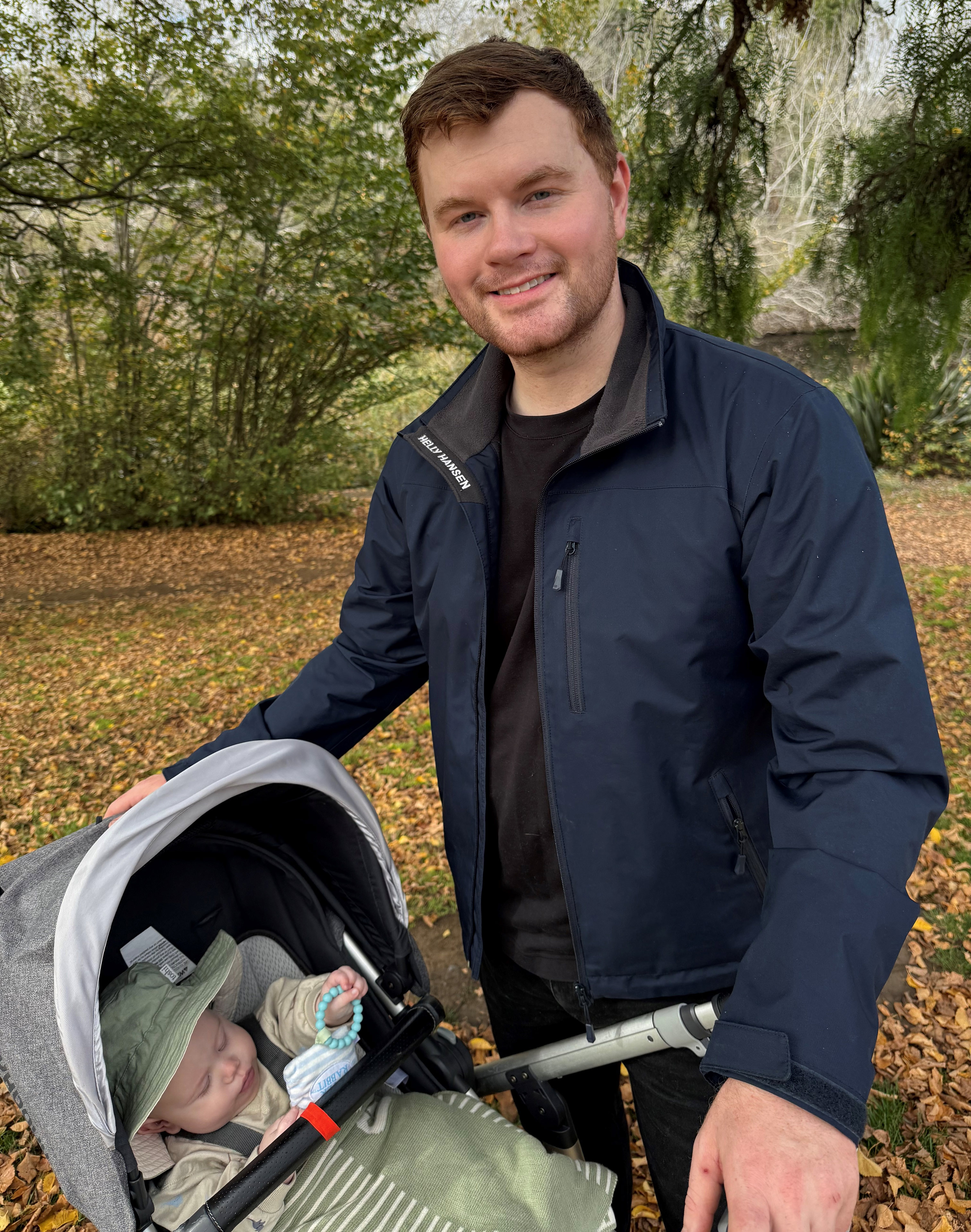 A photo of a man outside with a baby in a stroller.