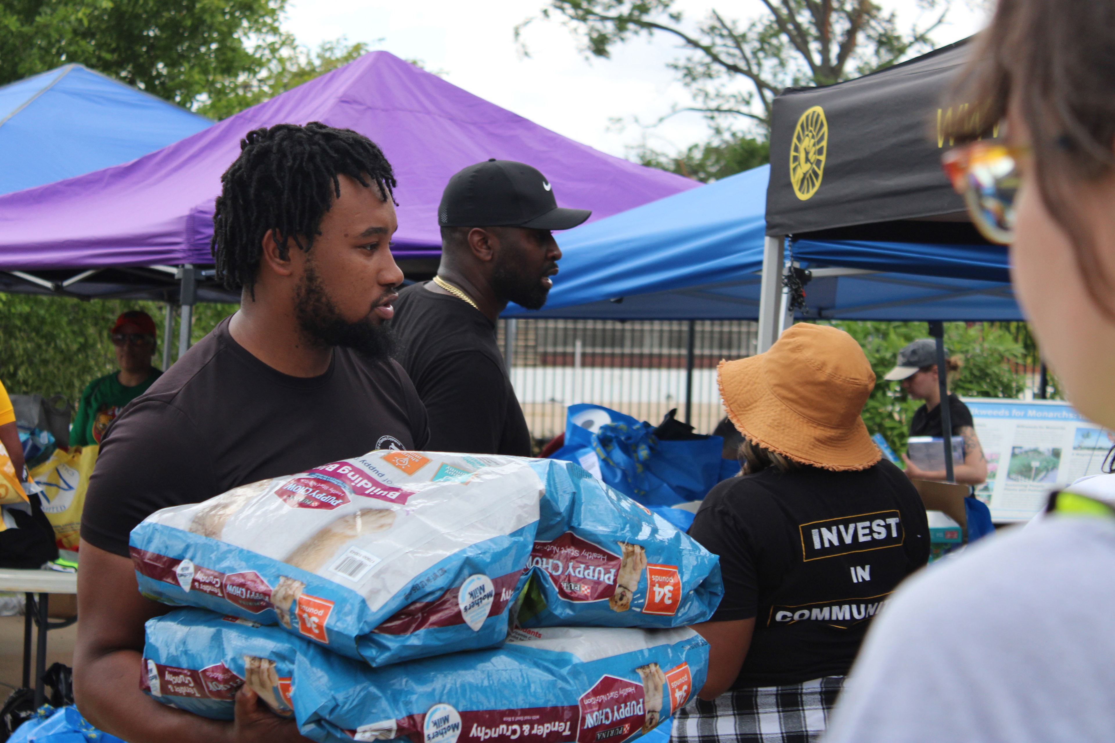 A photo of a man carrying two large bags of dog kibble.