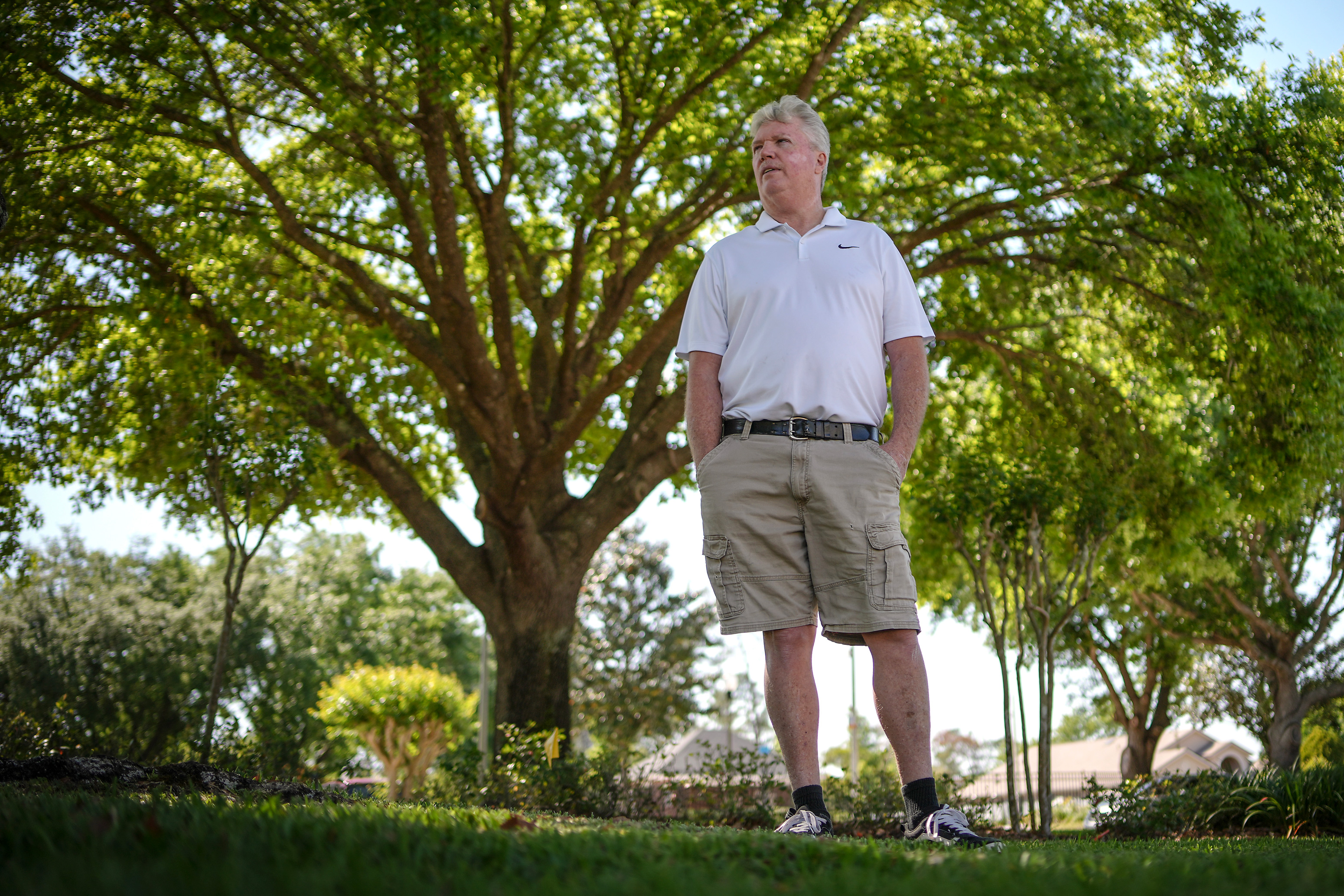 A photo of a man standing outside under a shaded canopy of trees.