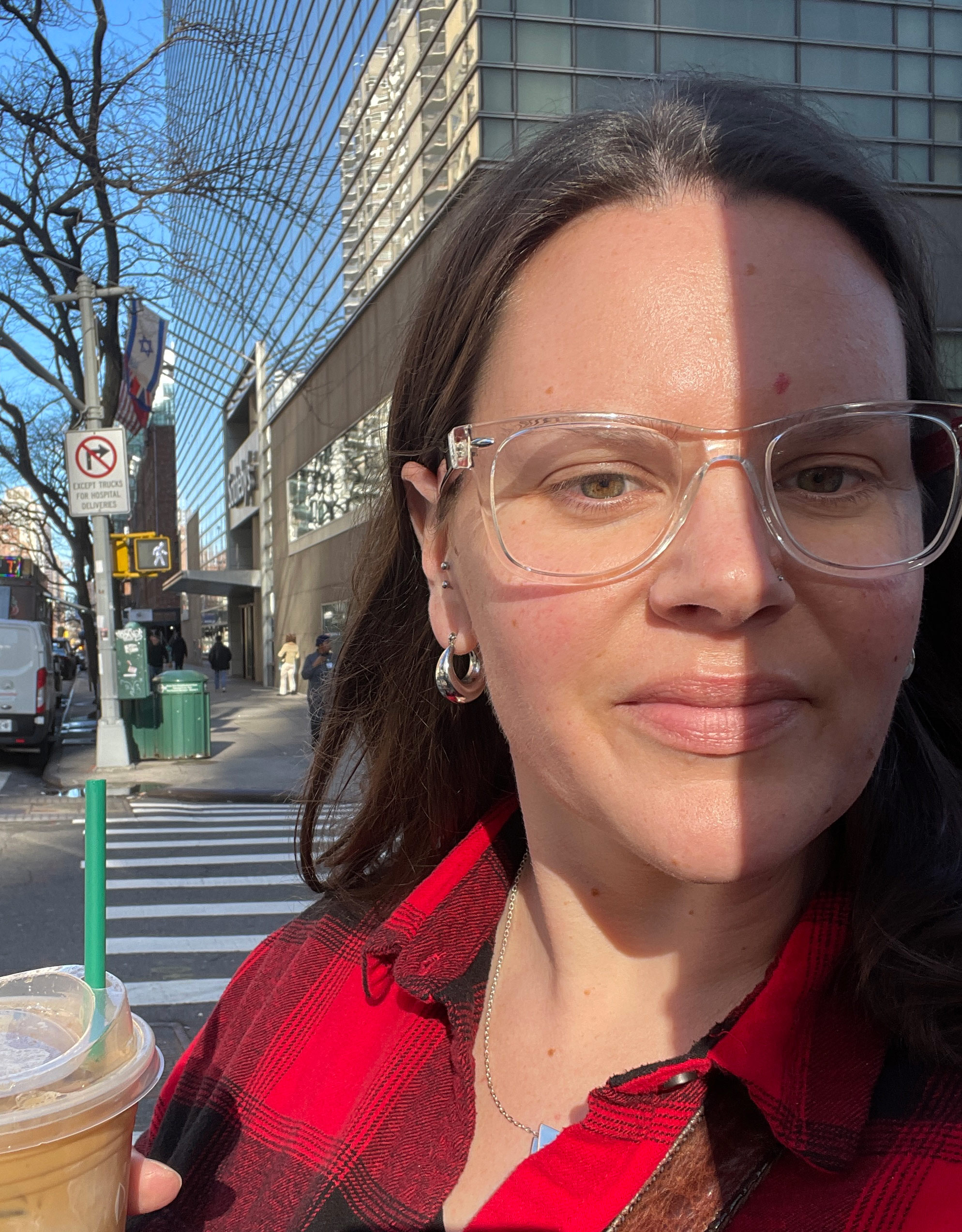 A selfie taken by a woman outside. Half of her face is in shadow.