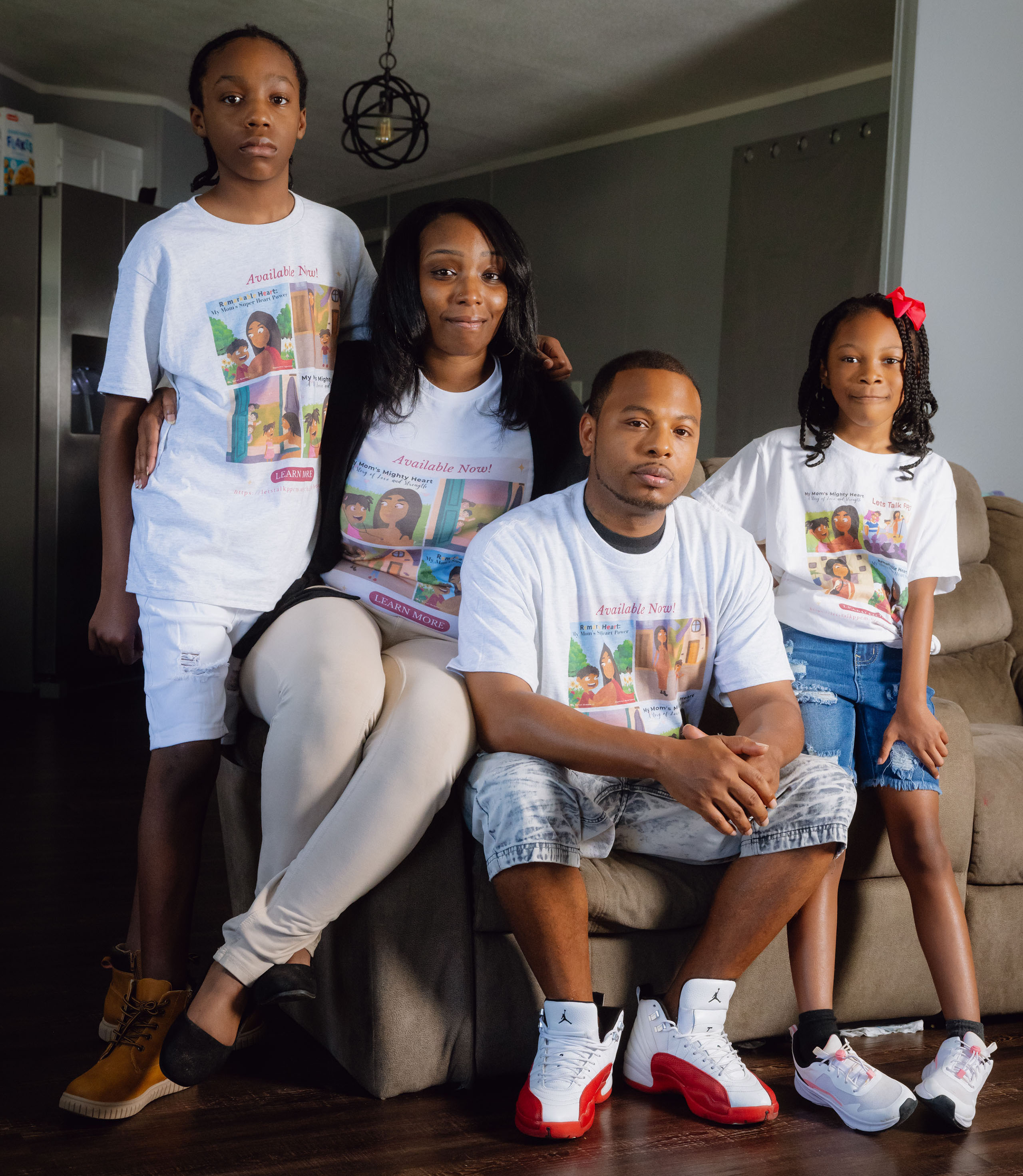 A family portrait taken indoors. From left to right, the adolescent son, mother, father, and young daughter. They are wearing matching T-shirts.