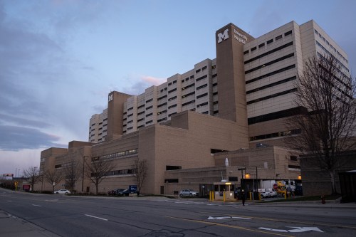 An outside view of the University of Michigan Hospital, a tan building with a large M on the outside