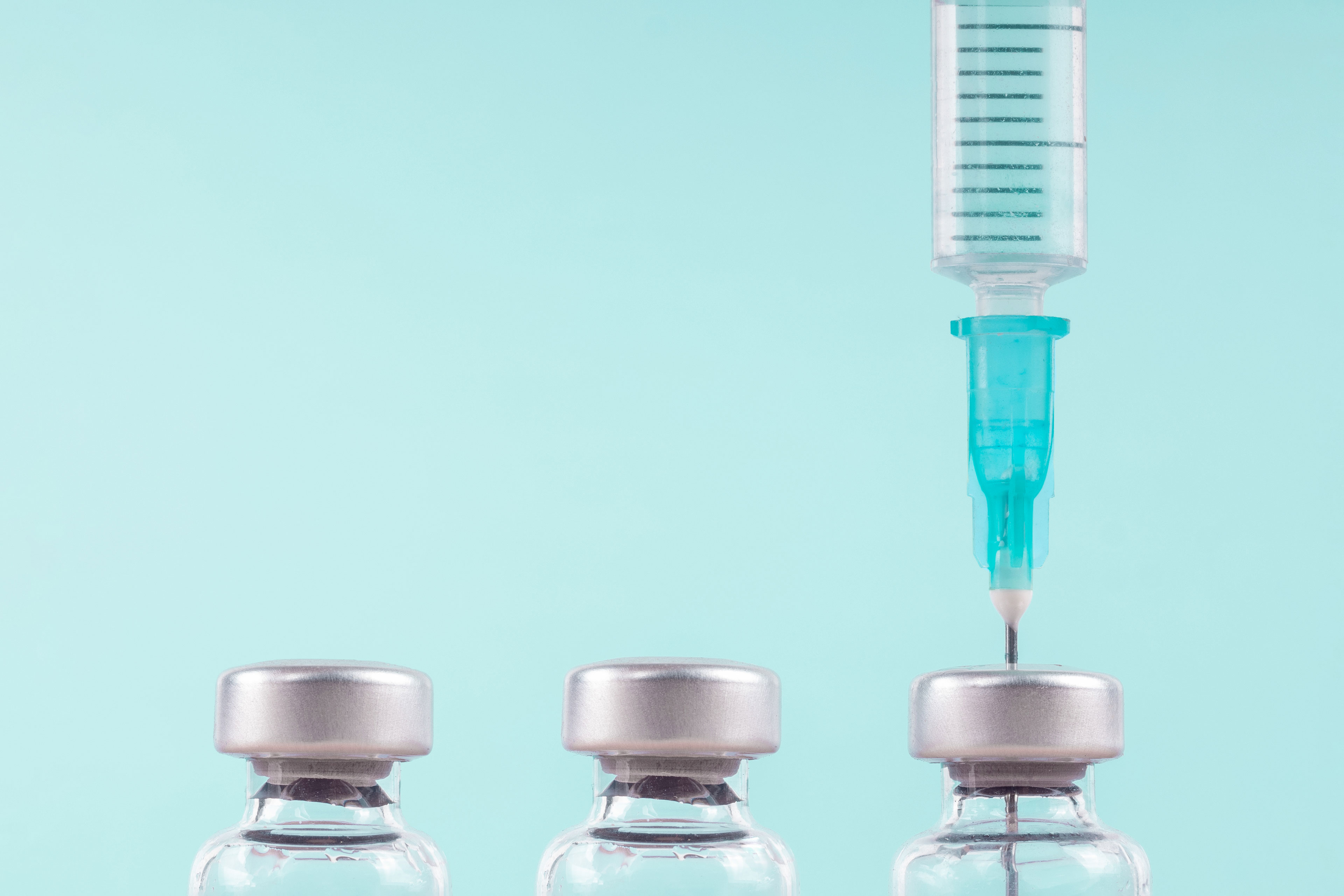 A row of three vials with a syringe sticking out of the third.