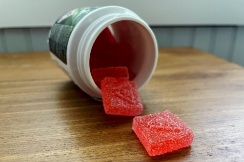 A bottle of red, sugar-coated cannabis gummies.