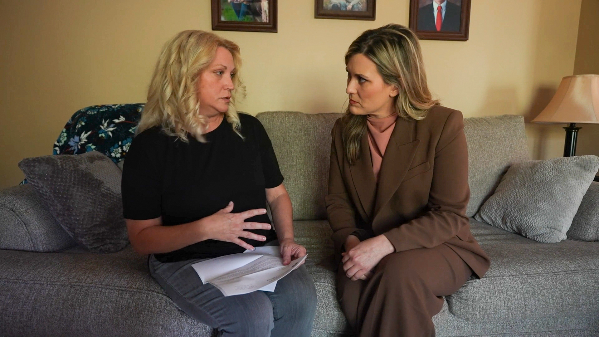 A photo of two women seated on the couch. The woman on the left has a denial letter in her lap.