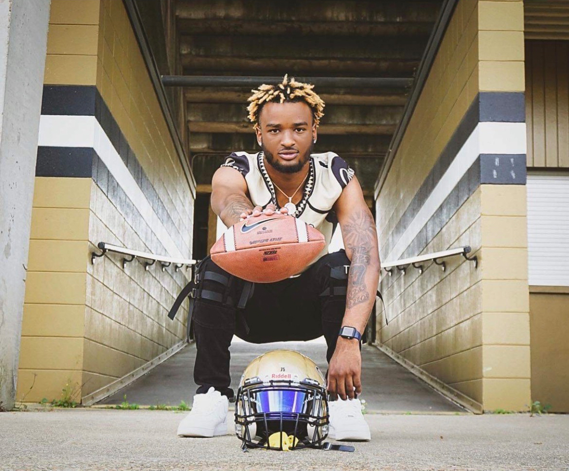 A photo of Tajdryn Forbes posing with a football and his helmet.