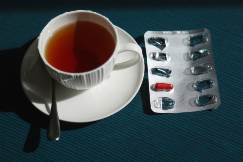 A photo of a cup of tea with a blister pack of iron pills next to it.