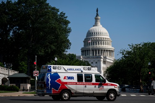 A photo of an ambulance driving by in Washington, D.C. The rotunda of the U.S. Capitol is prominent in the background.