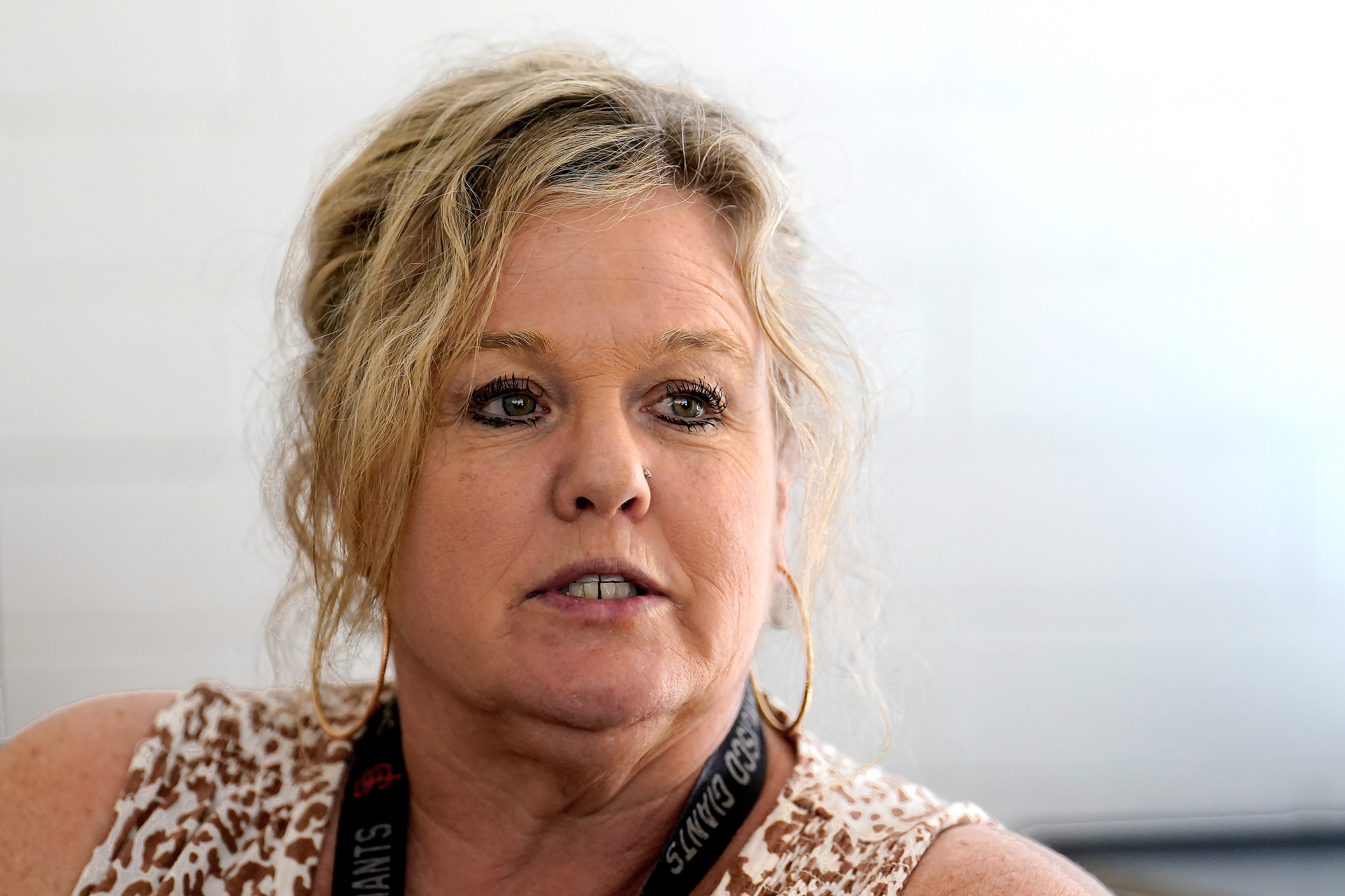 A woman with blond hair looks off camera while talking