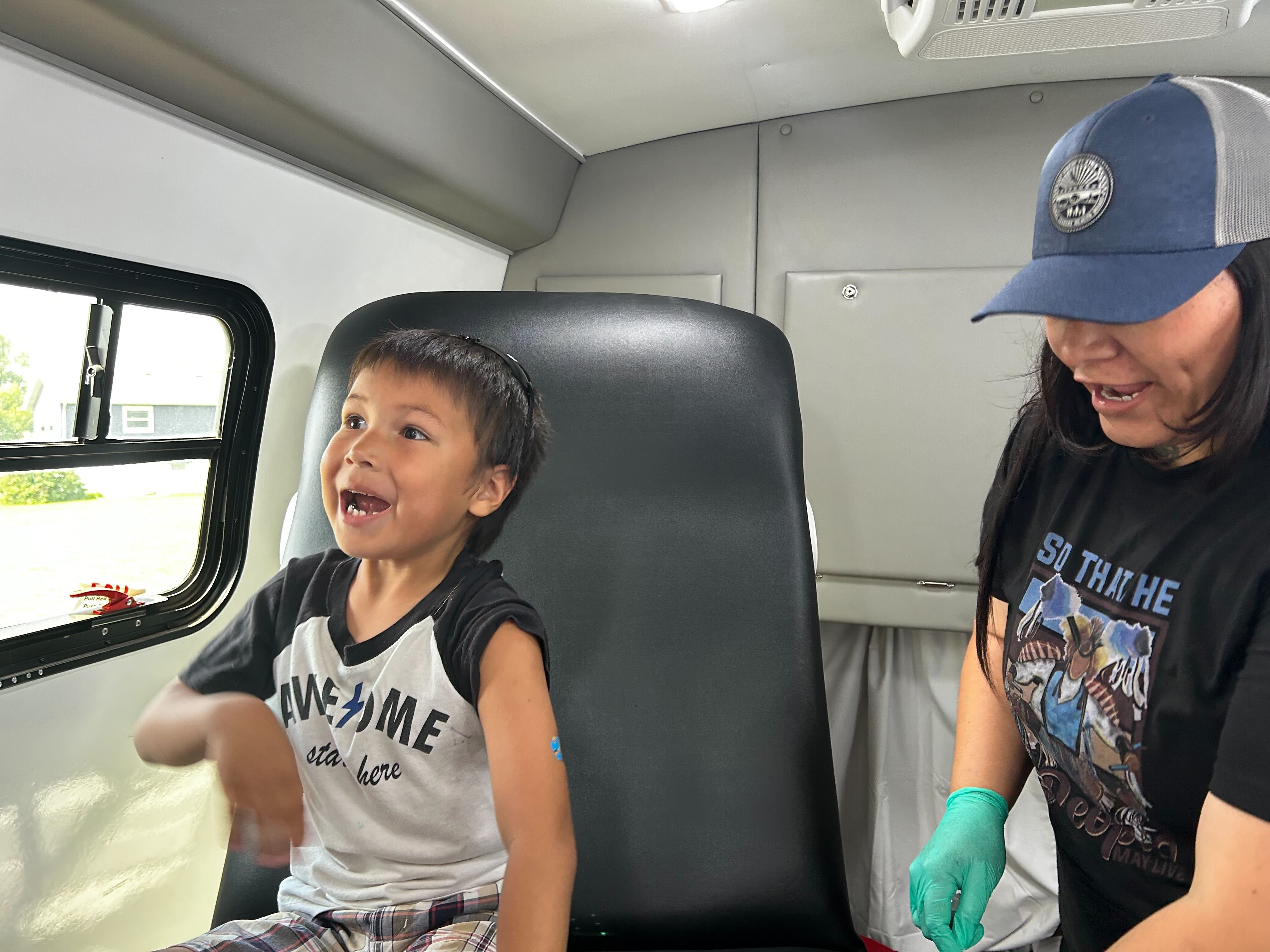A photo of a young boy with a bandage on his arm, smiling after receiving a vaccine.