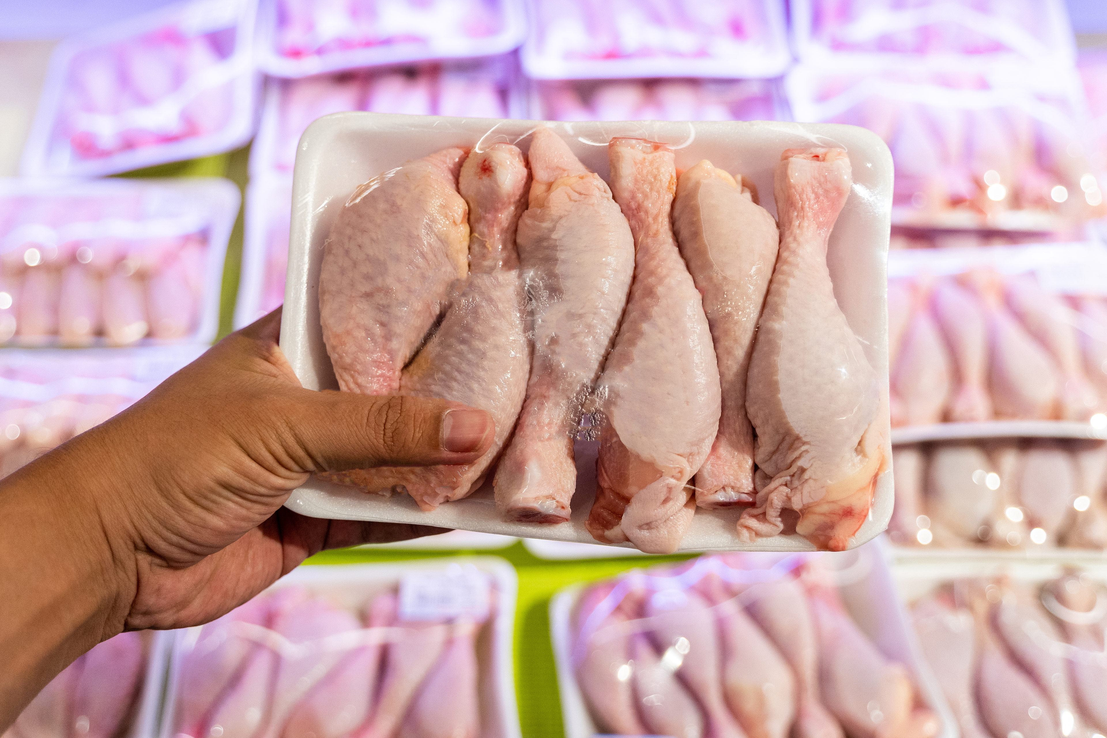A photo of someone holding a pack of chicken legs at a grocery store.