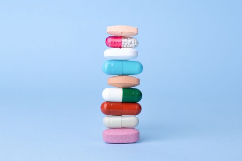 An up-close artistic photo of a stack of different multi-colored pills.