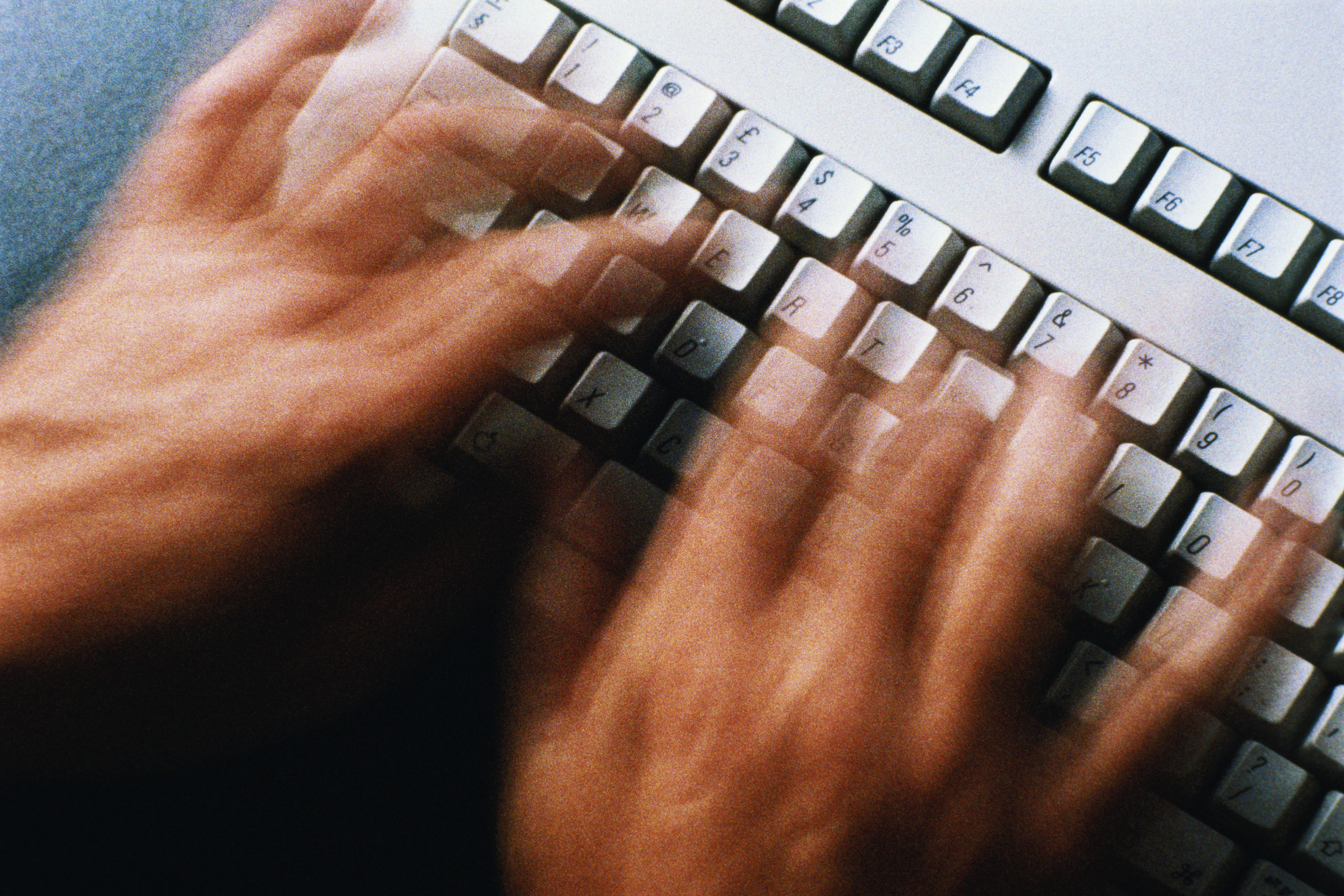 A photo of hands typing on a keyboard.