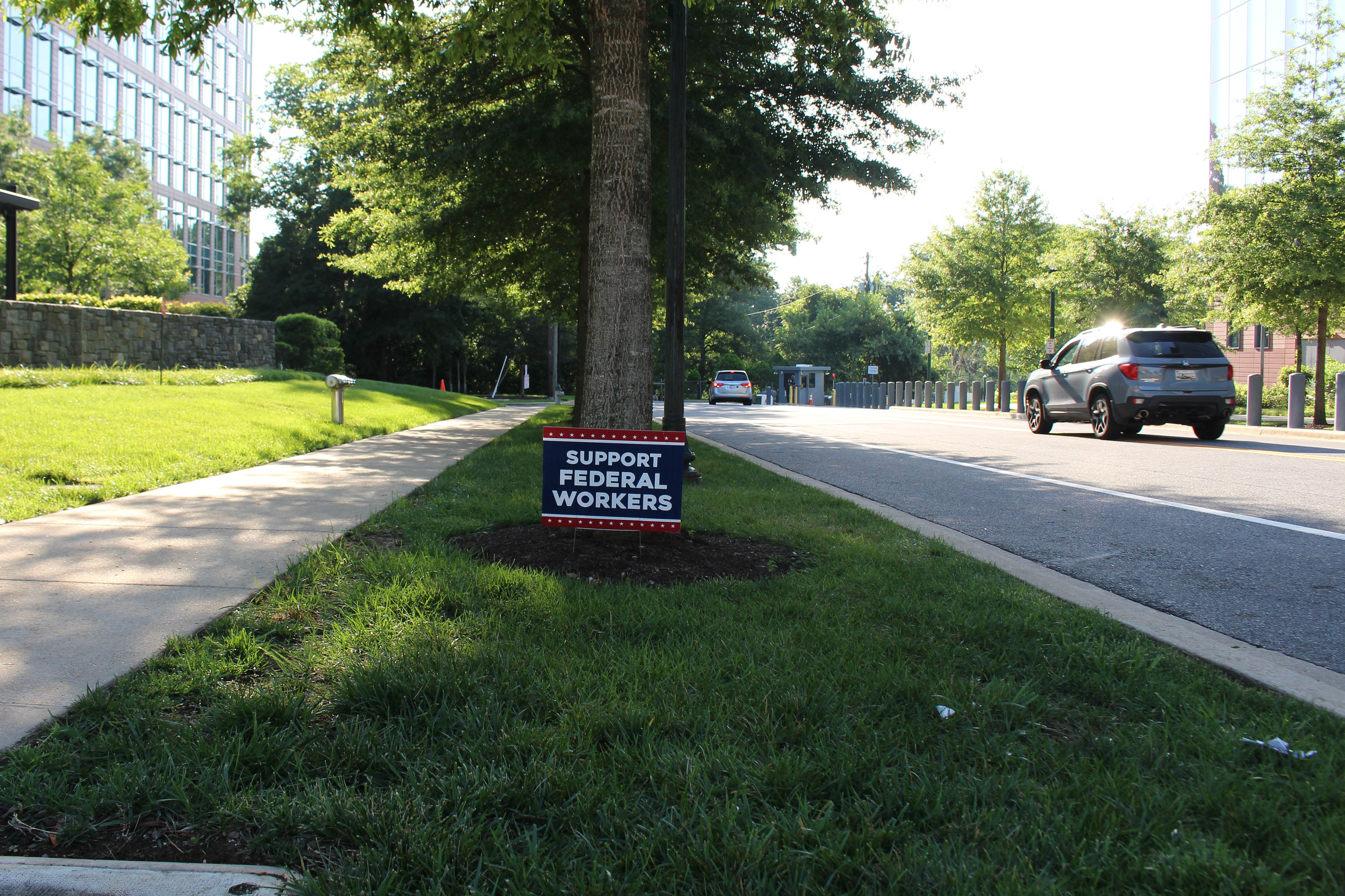 A lawn sign near a sidewalk reads, "support federal workers."