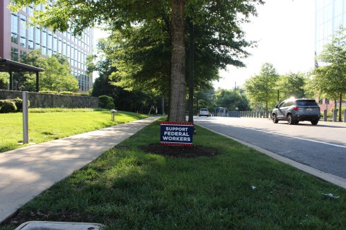 A lawn sign near a sidewalk reads, "support federal workers."