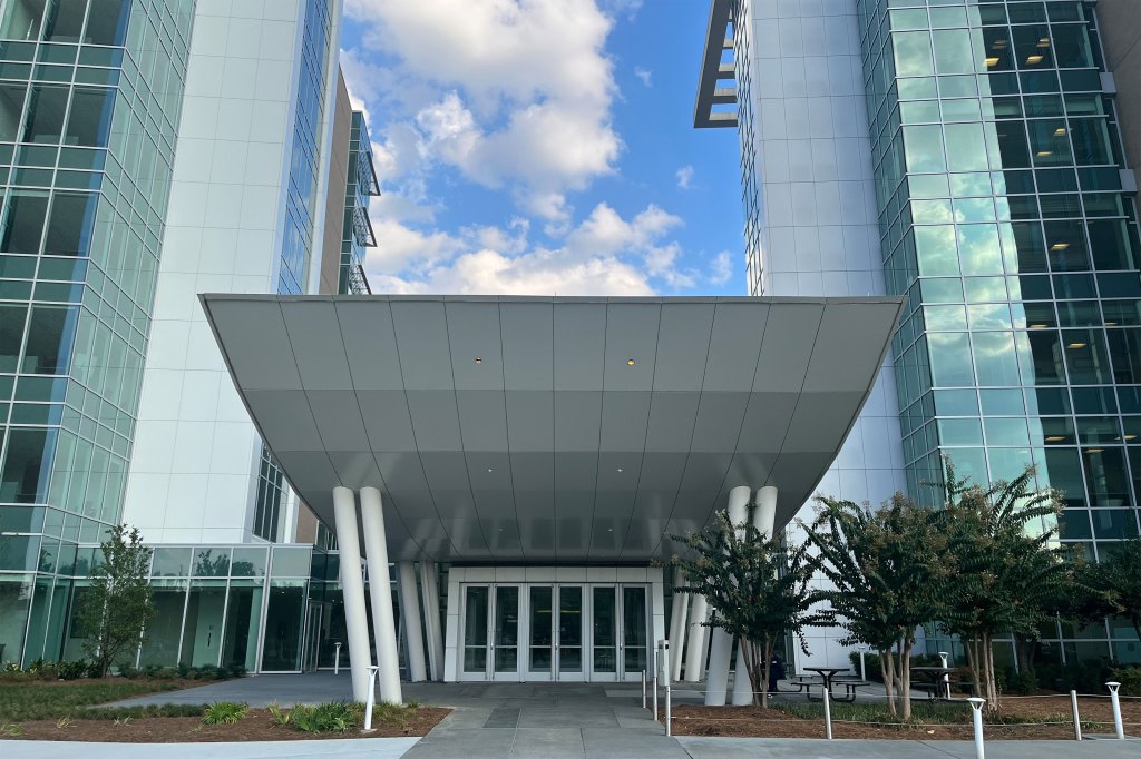 An entrance to a building is between two towers with many glass windows.