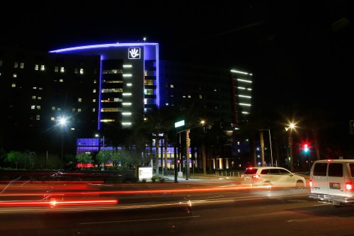 A photo of Phoenix Children's Hospital illuminated at night as cars drive by.