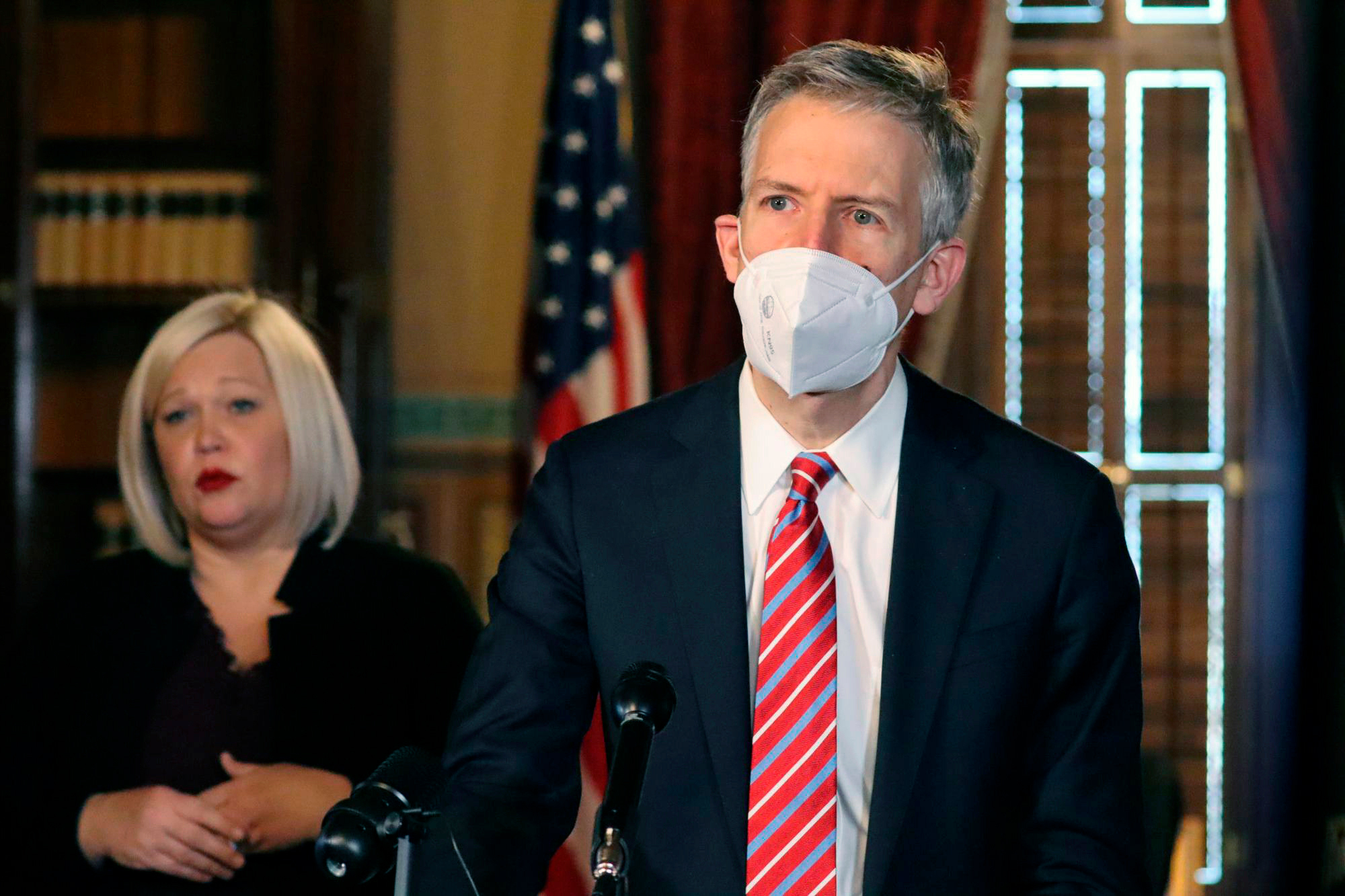 A photo of a man in a suit wearing a KN-95 mask at an official event.